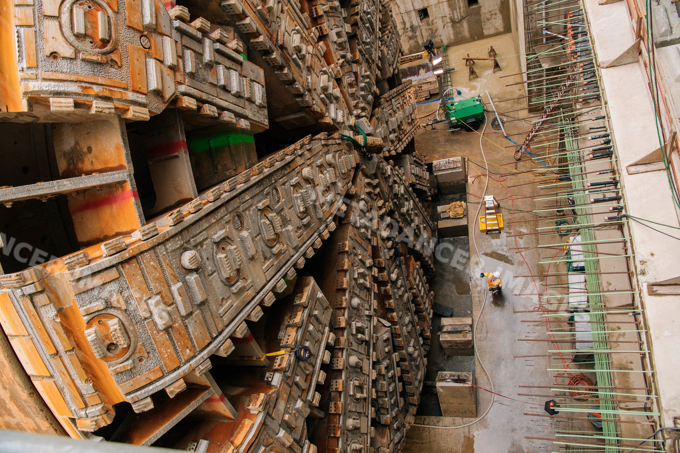 Two white workers observe tunnel boring machine drilling underground