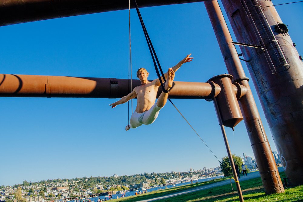 Man performing aerial silk exercise outdoors in Seattle park