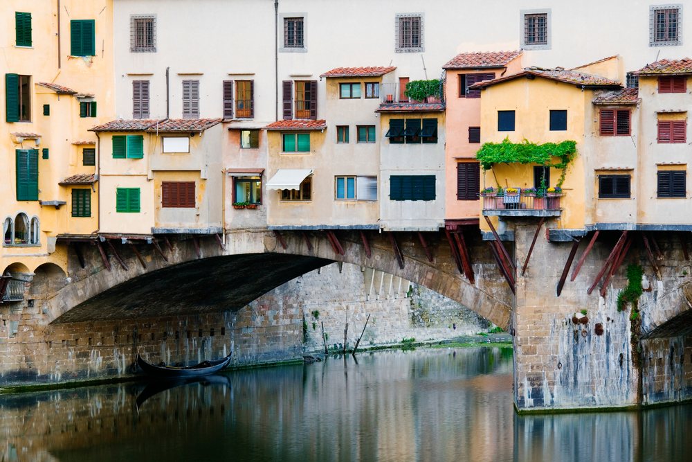 Ponte vecchio stone bridge with buildings over arno river, tuscany