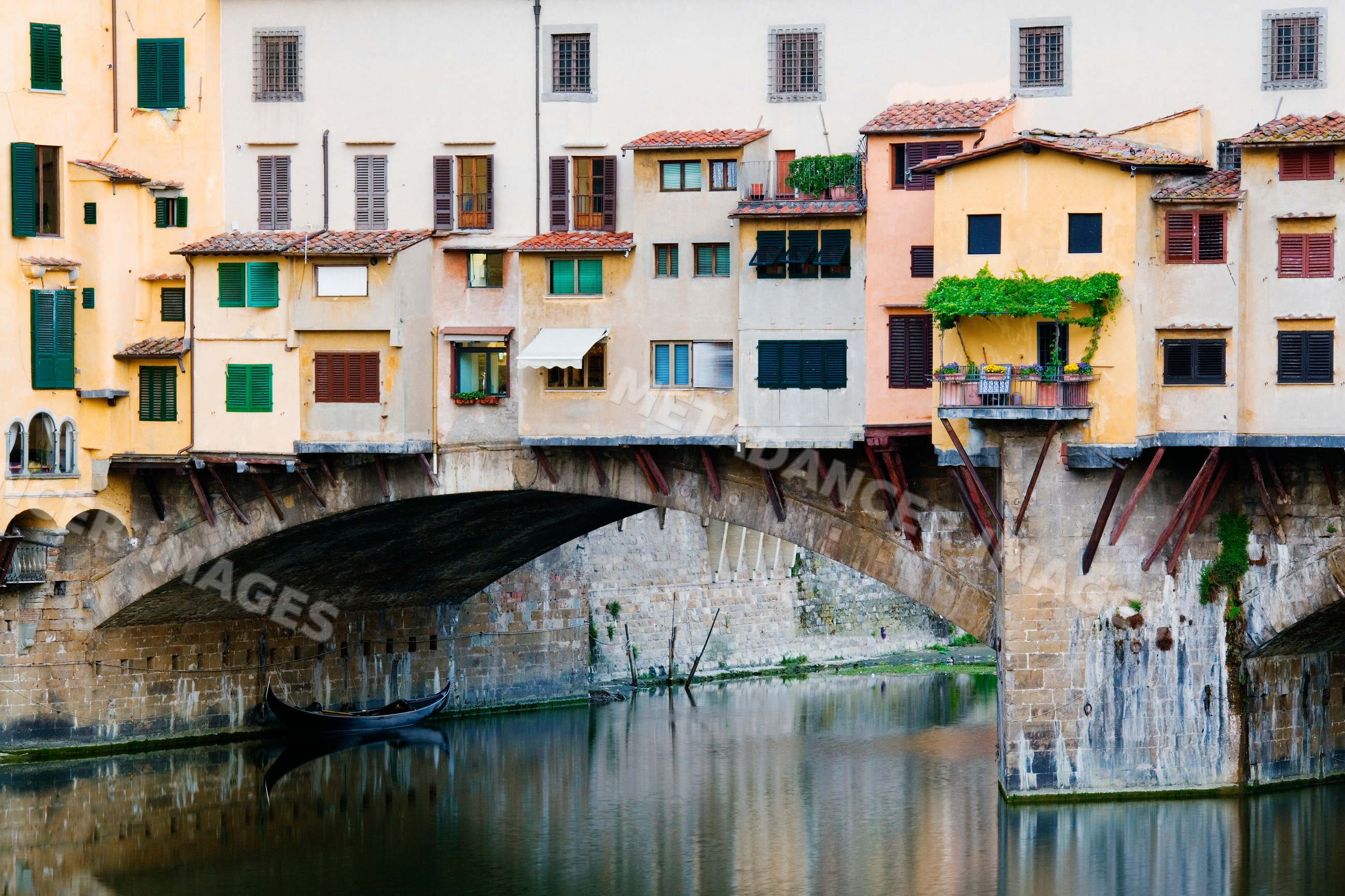 Ponte vecchio stone bridge with buildings over arno river, tuscany
