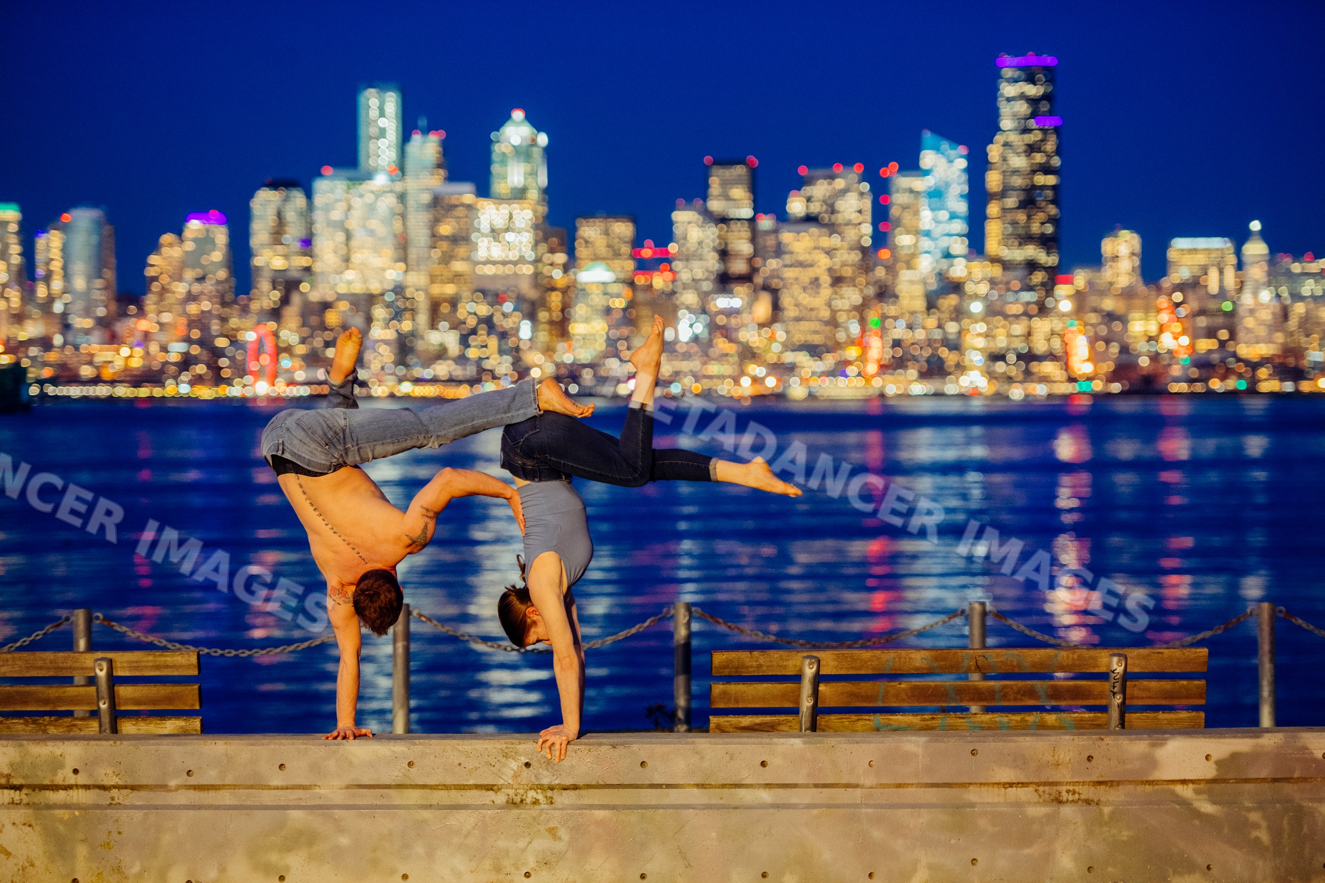 Partner acrobatics handstands by Seattle waterfront at night