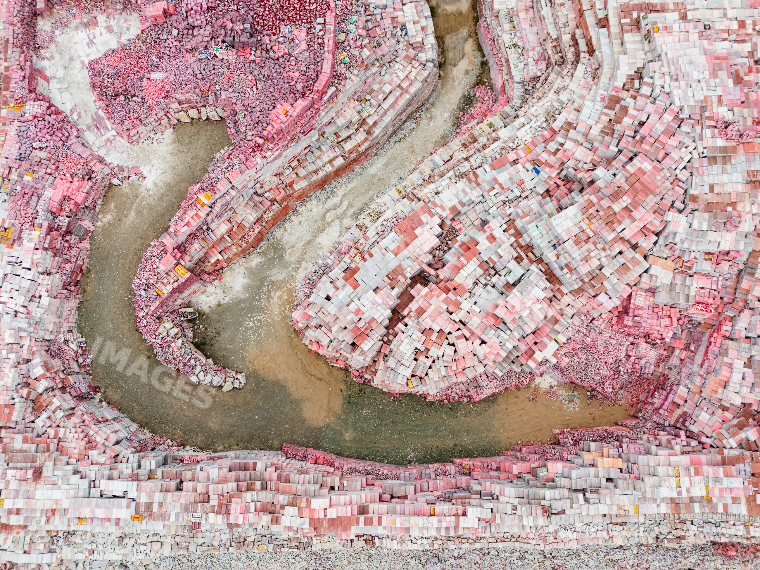 Aerial view of stacked pink stone blocks and riverbed
