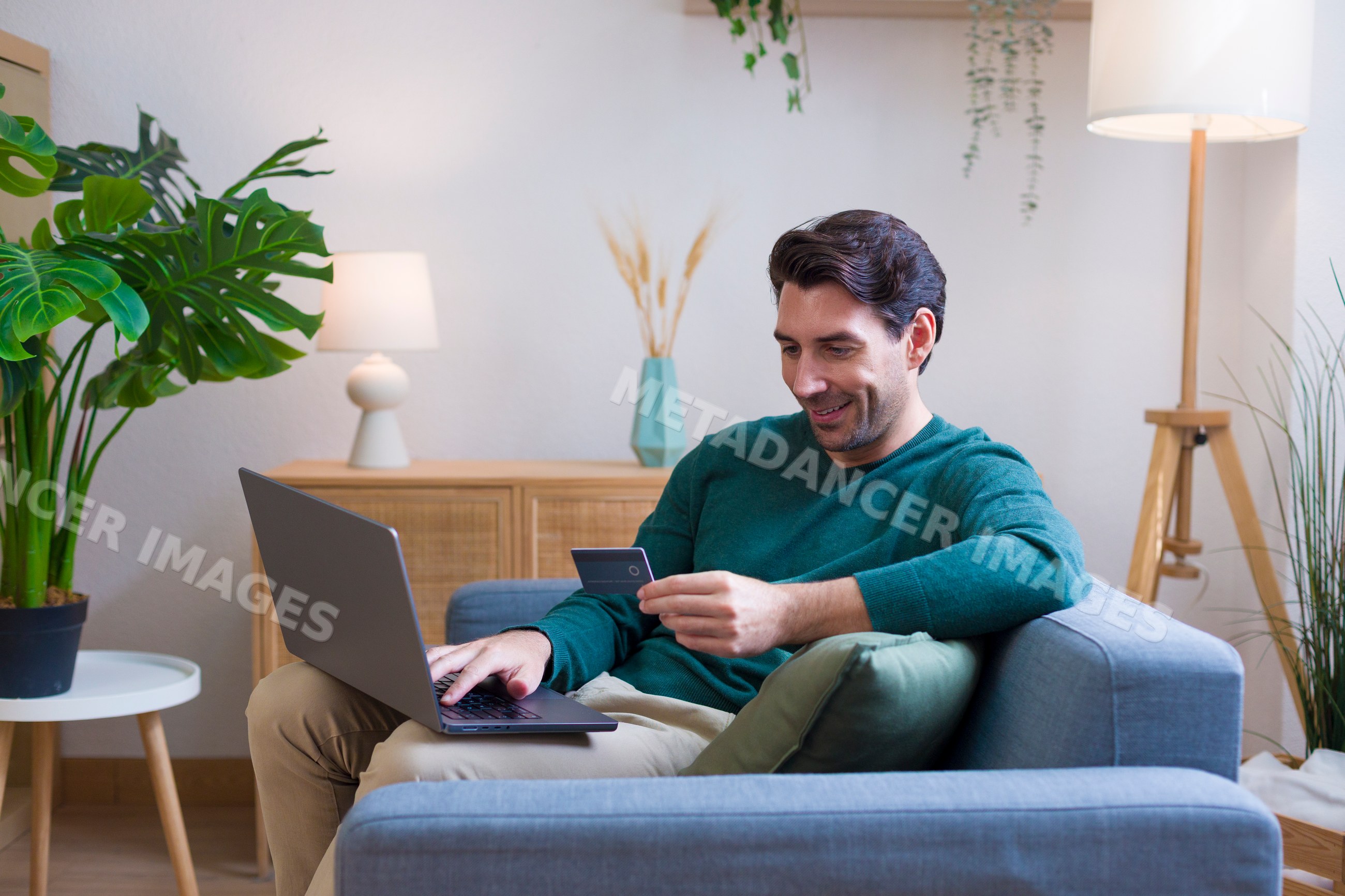 White man using laptop and holding credit card