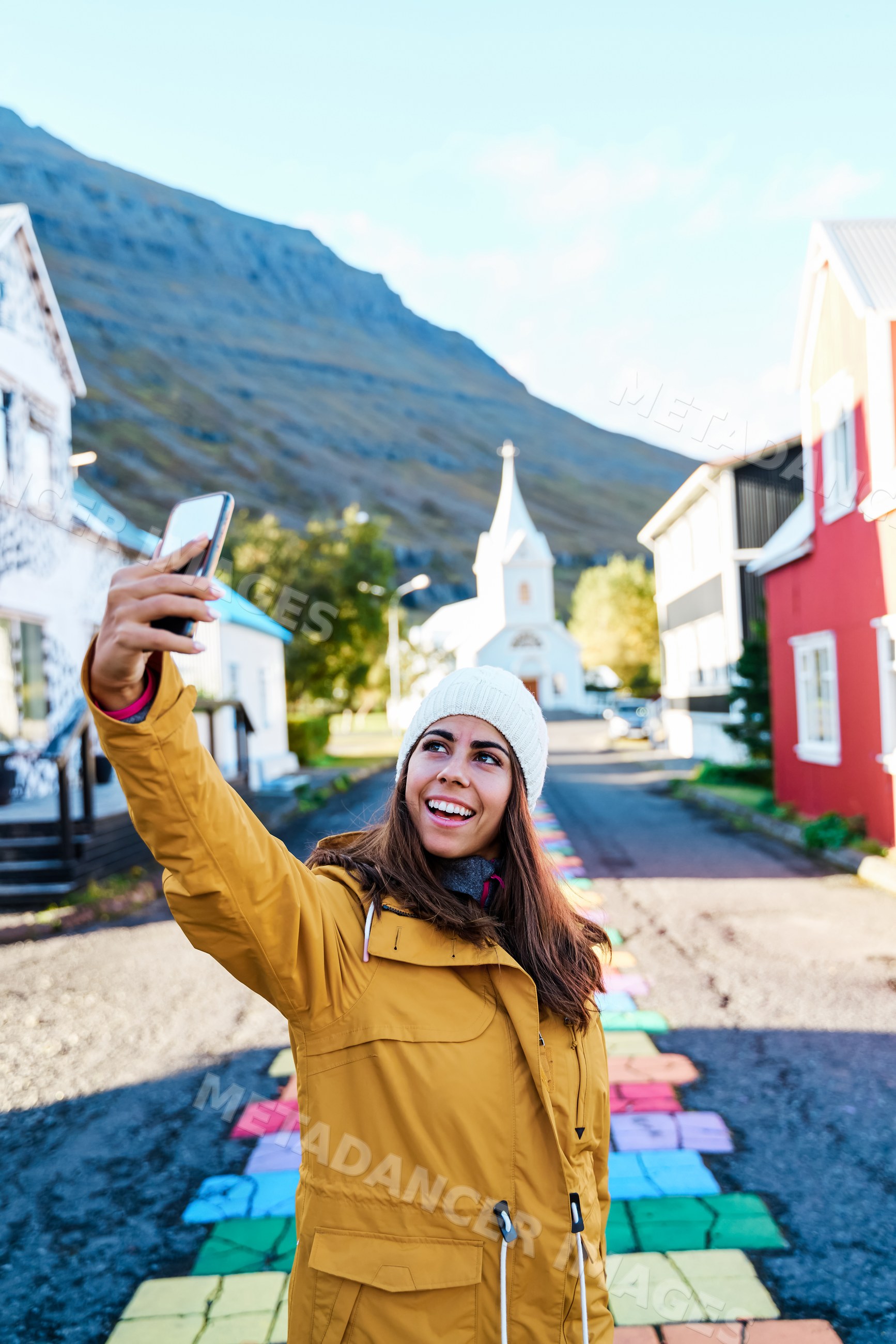 A white woman takes a selfie on a colorful street path