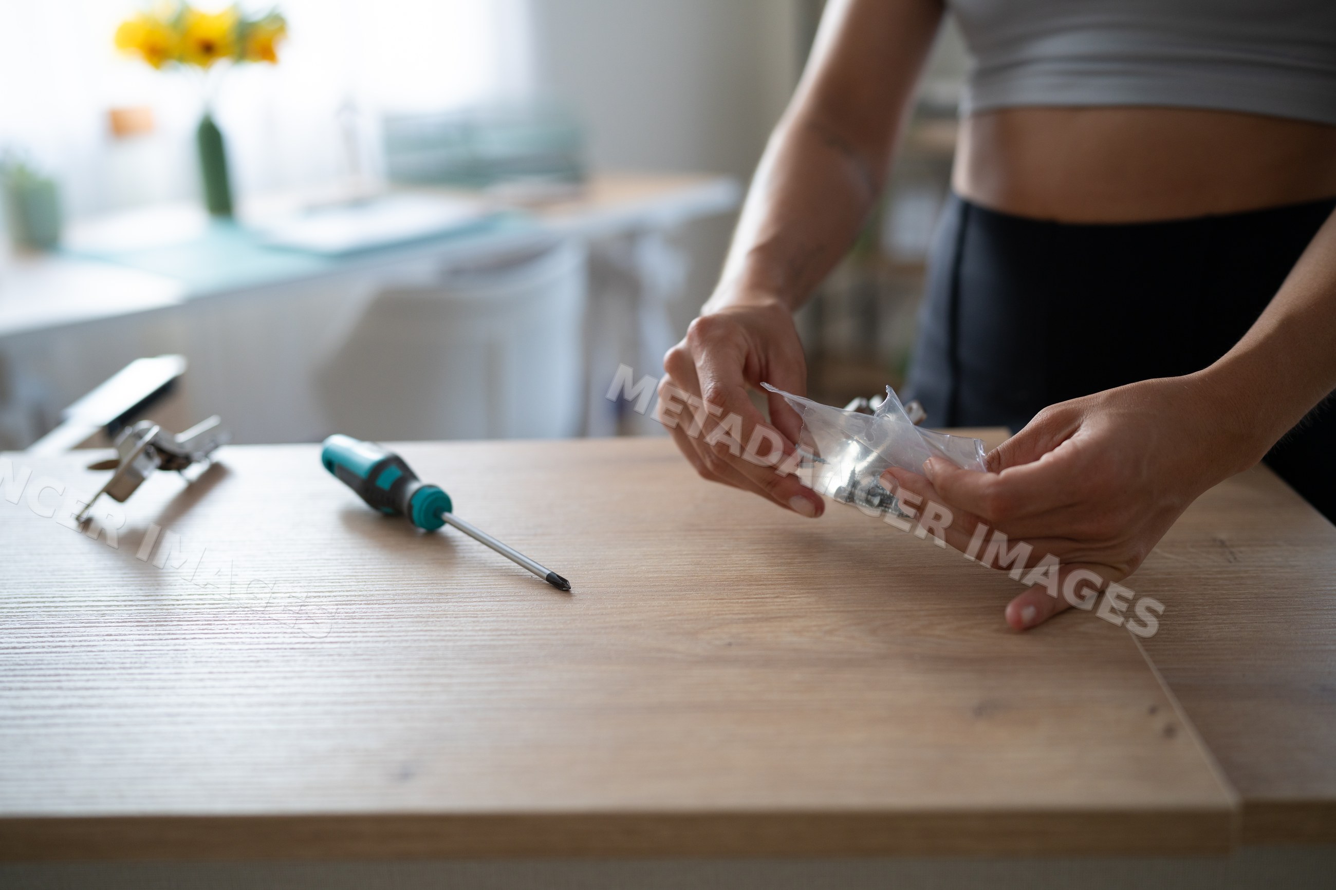 A white person assembling wooden furniture by unpacking screws