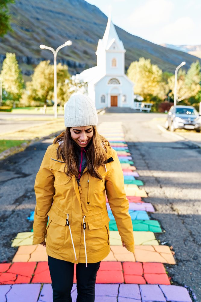 A white woman walks on a colorful sidewalk near a church in Iceland