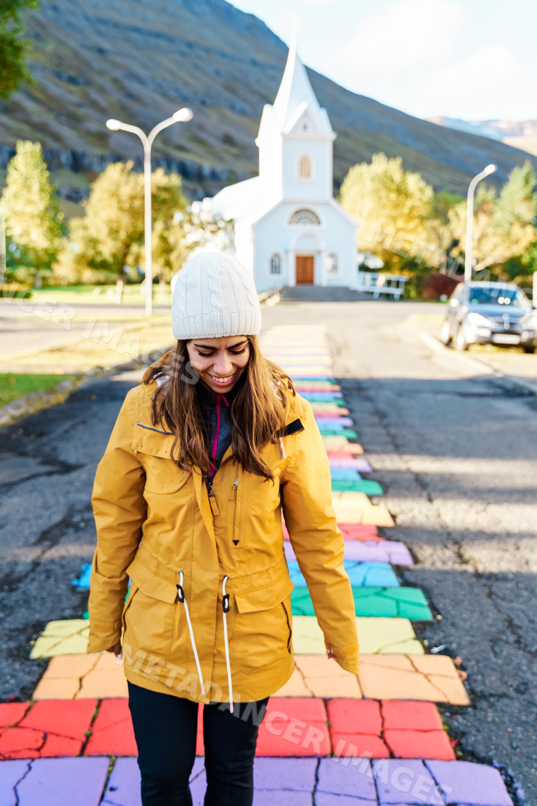 A white woman walks on a colorful sidewalk near a church in Iceland