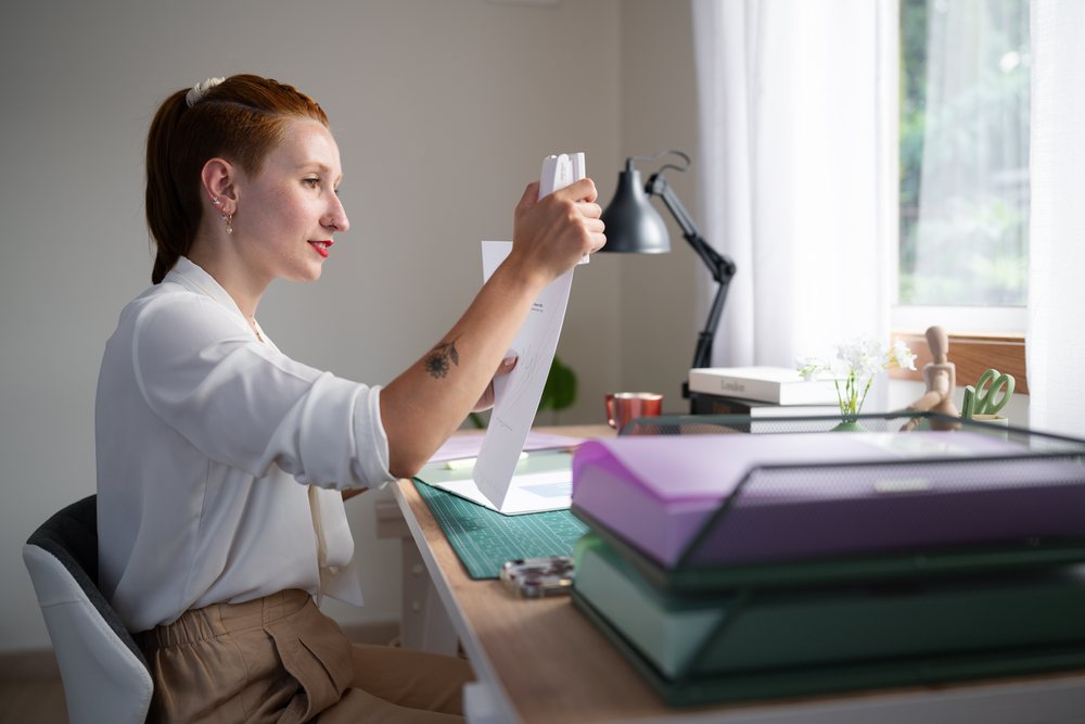 A white woman staples papers while working from home in Galicia, spain
