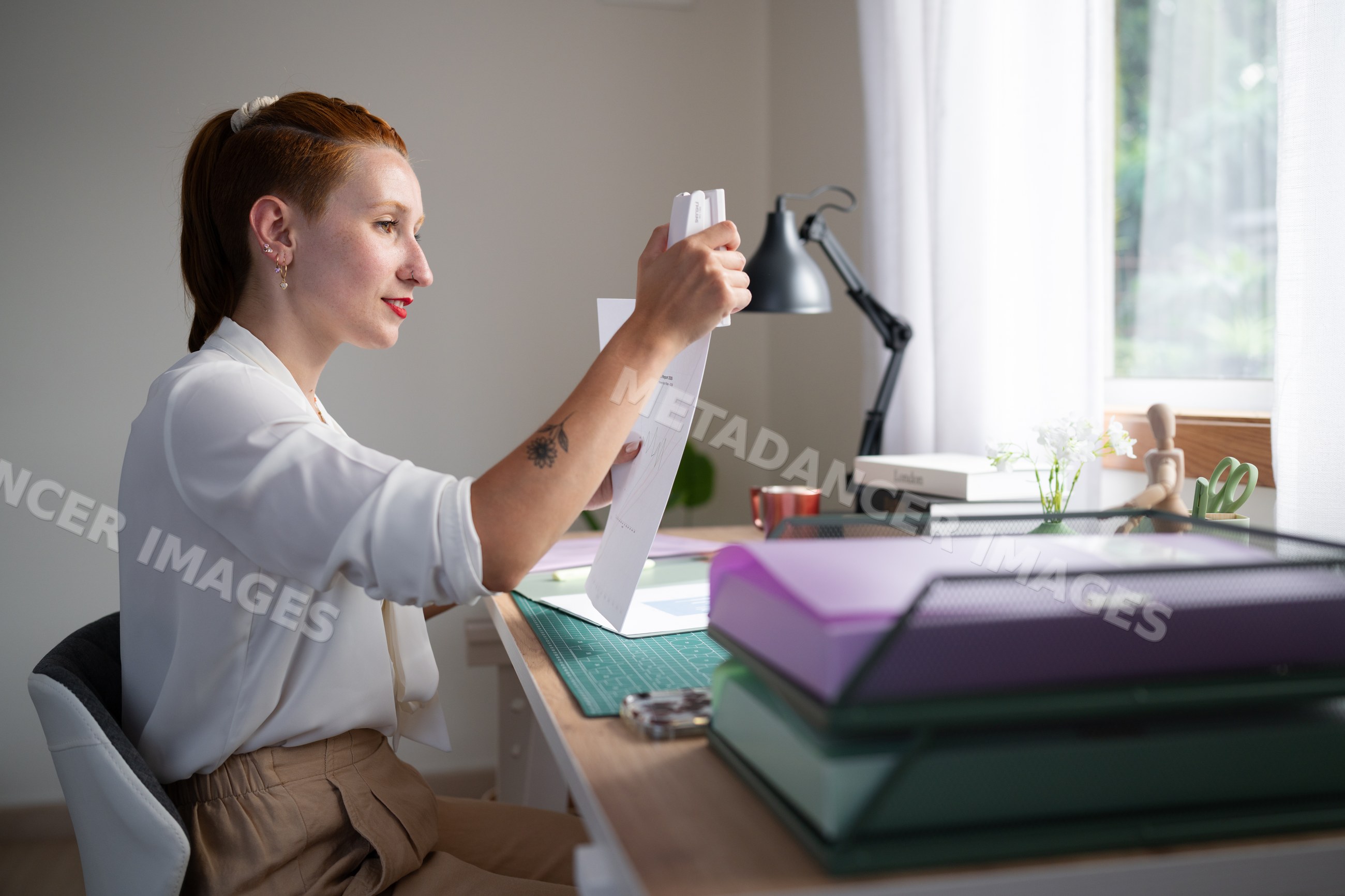 A white woman staples papers while working from home in Galicia, spain