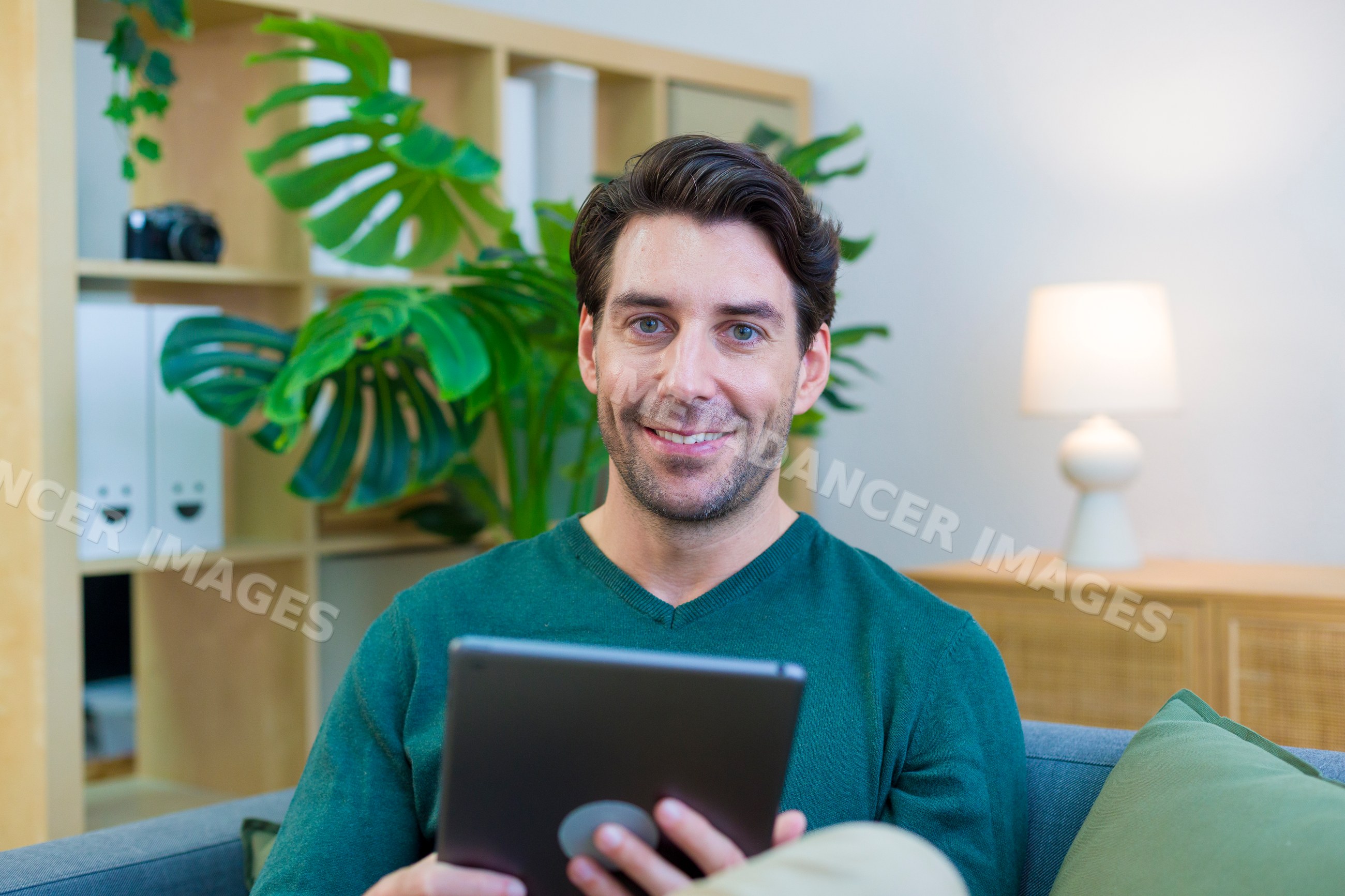 White man using a tablet in a cozy home living room