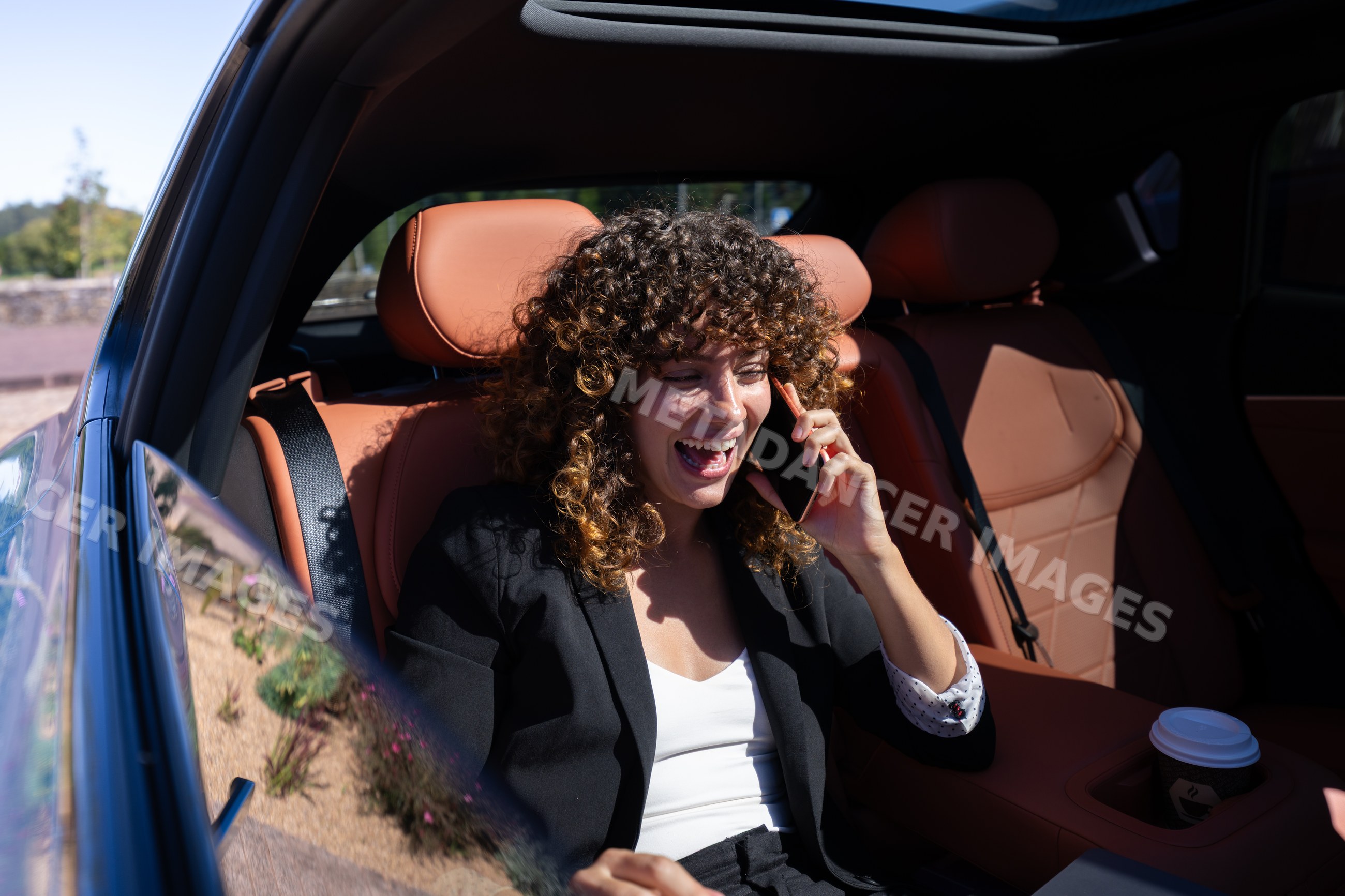 White woman talking on phone inside car with leather seats