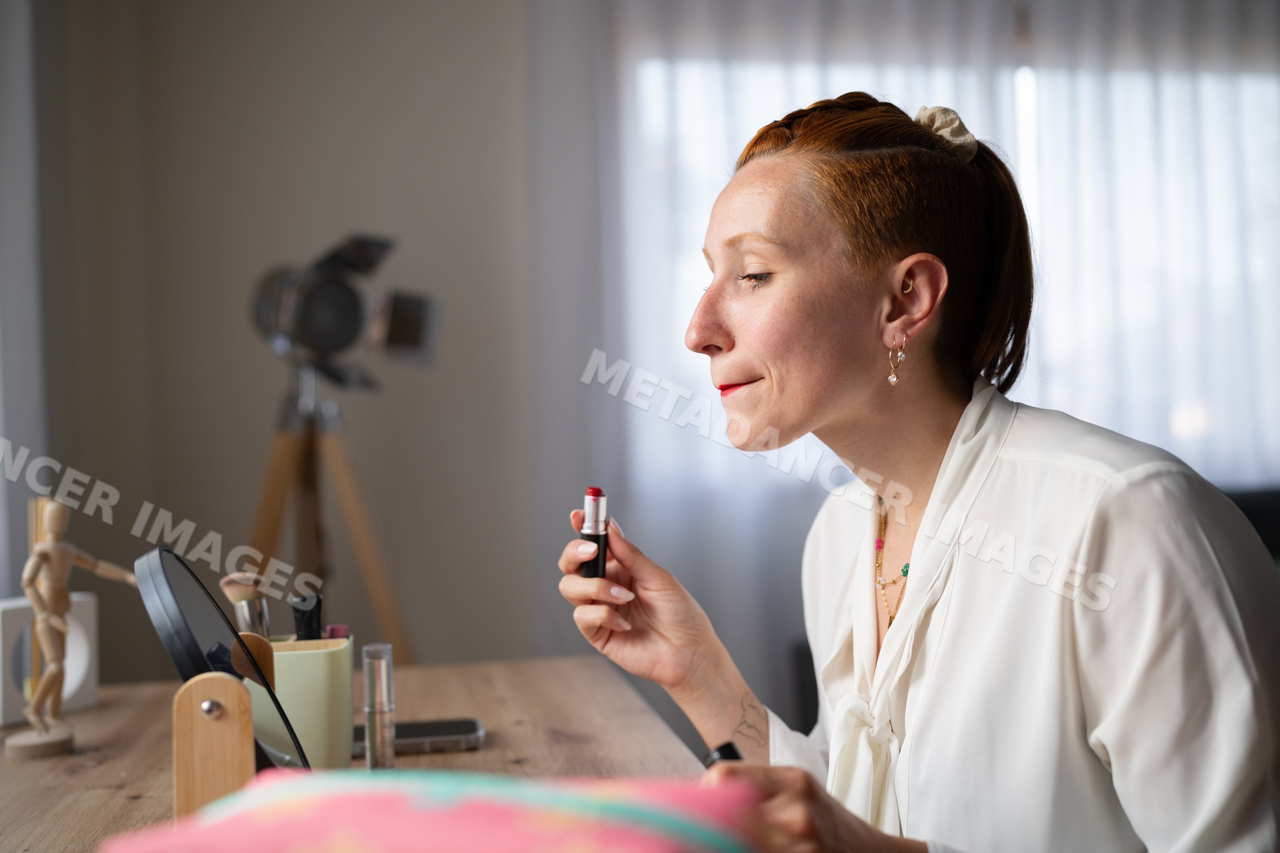 A white woman applying red lipstick