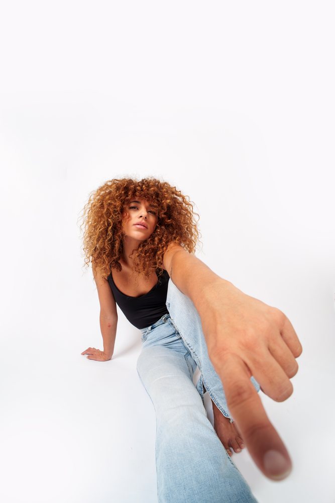 Hispanic woman with curly hair sitting and pointing
