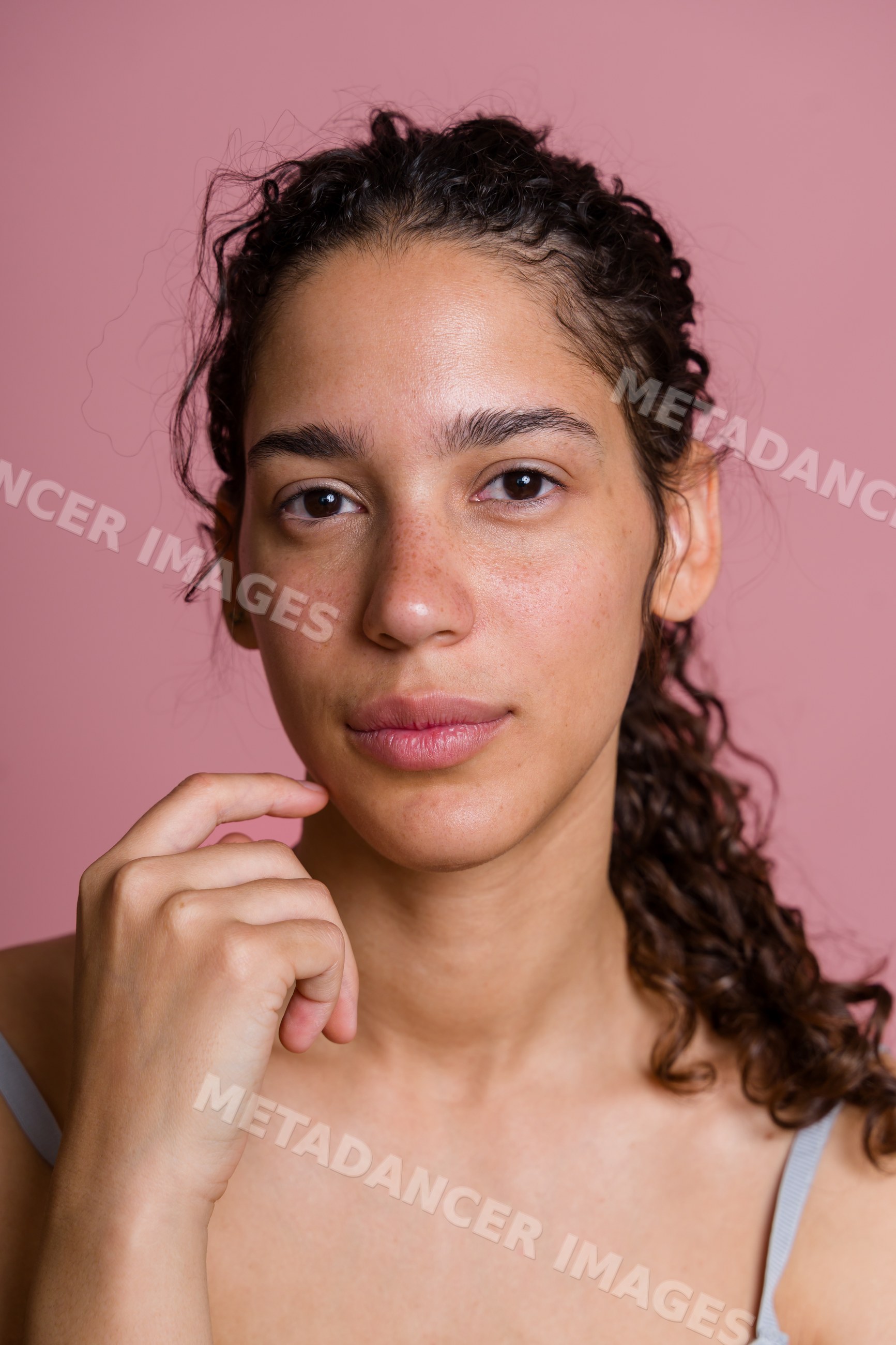 Portrait of young Hispanic woman with curly hair and freckles
