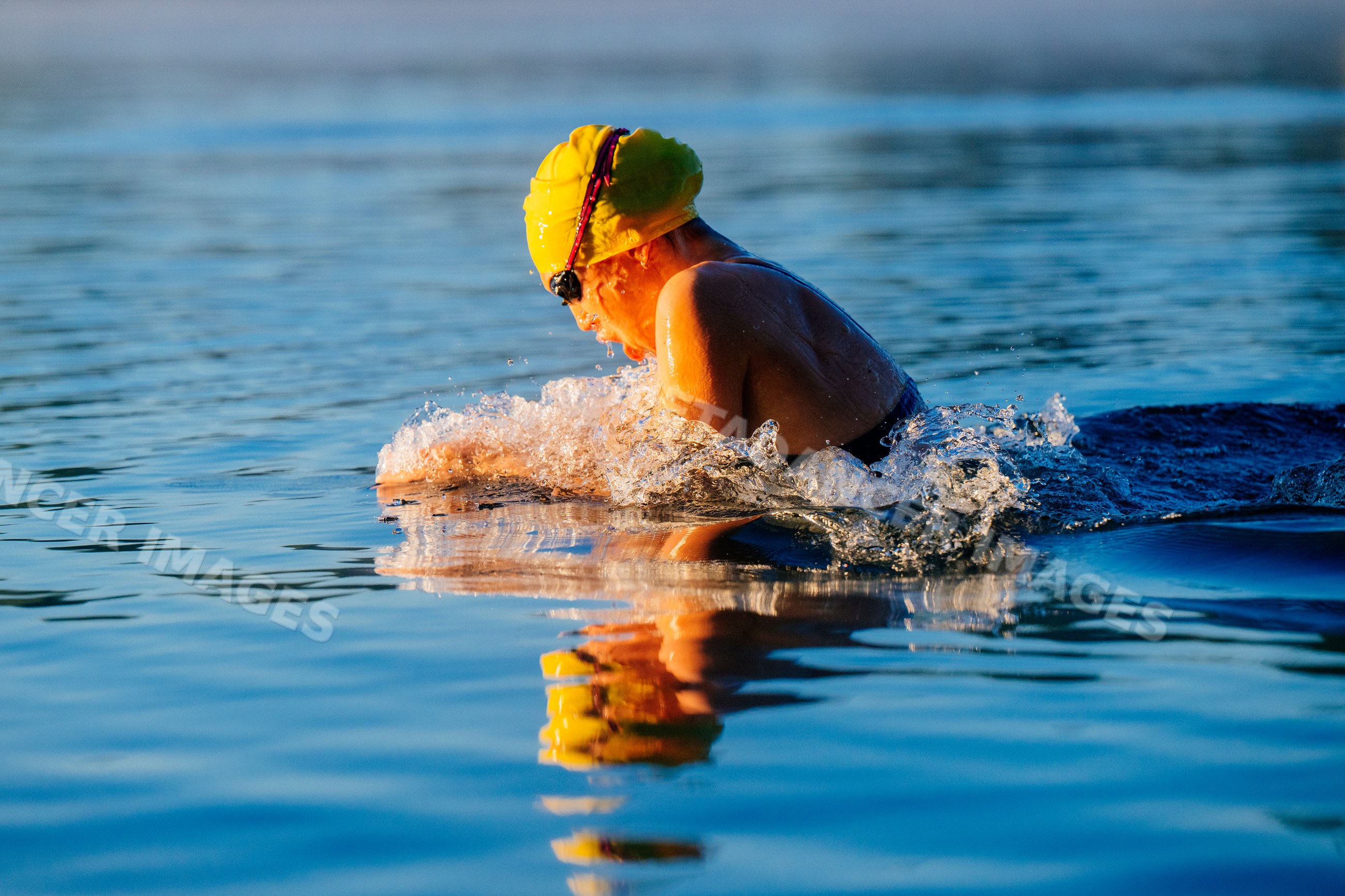 White swimmer performing breaststroke in open water at a lake