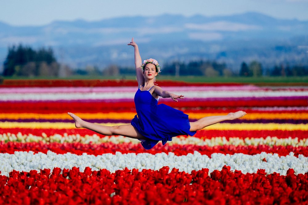 Ballet white dancer leaping over colorful tulip fields