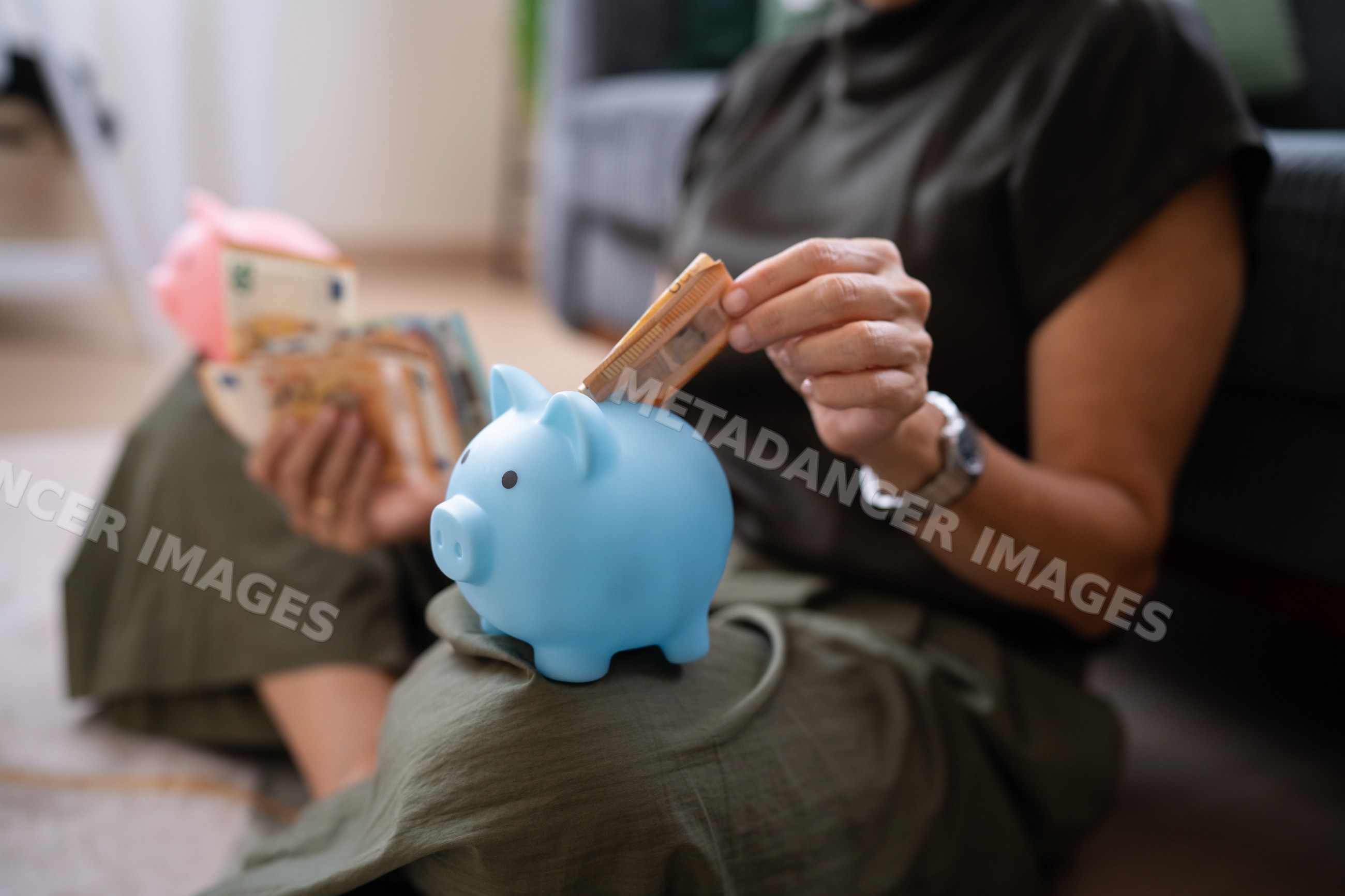 White person saving money by inserting euro banknote into blue piggy
