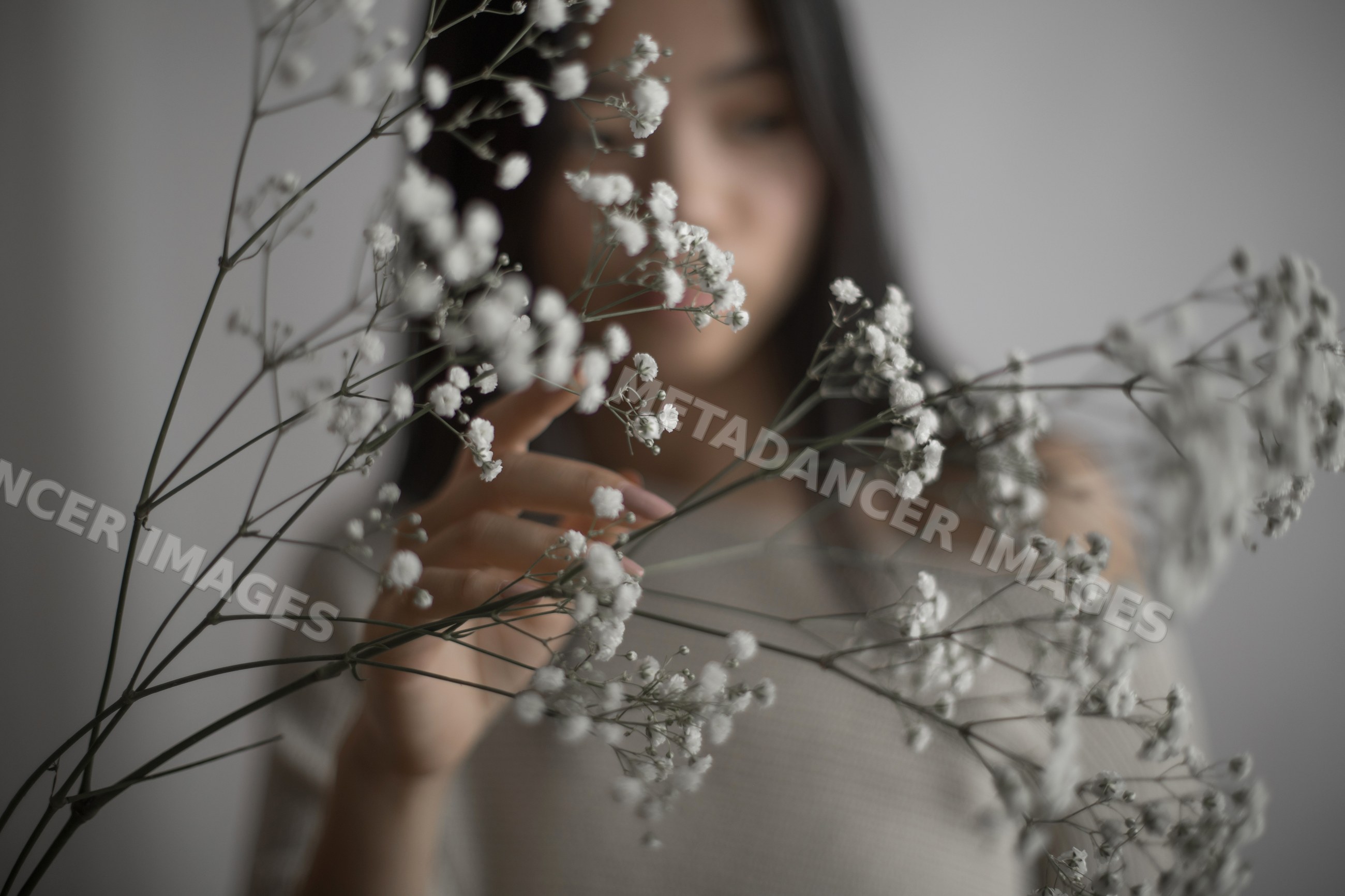 Southeast Asian woman touching delicate white baby's breath flowers