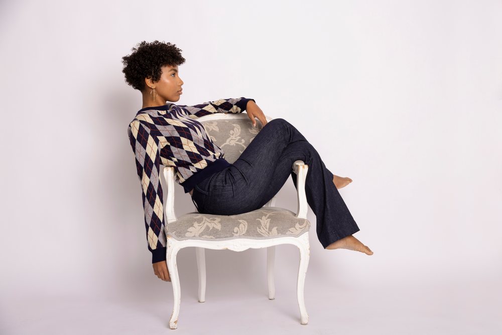 Hispanic woman wearing argyle sweater seated barefoot