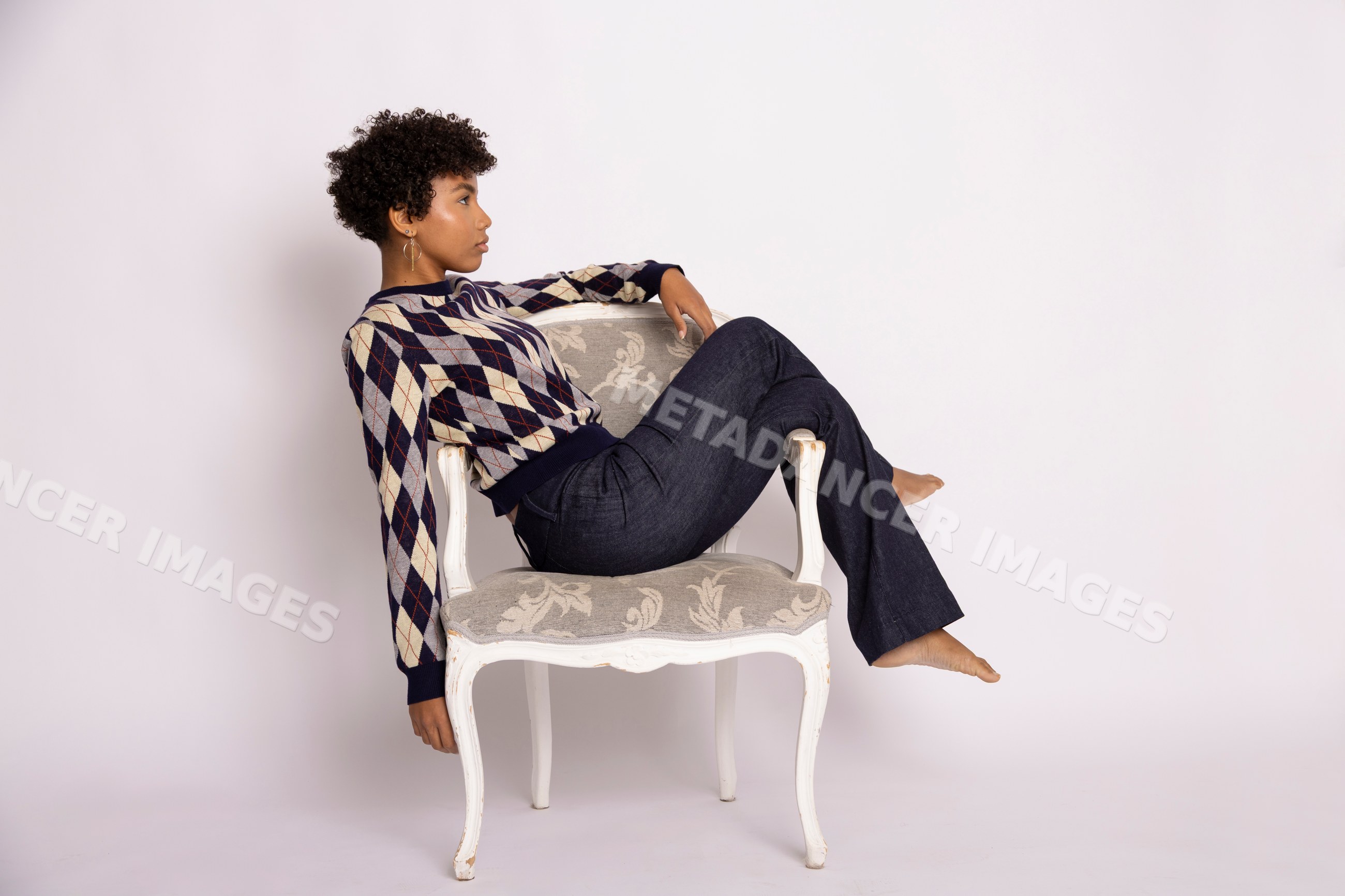 Hispanic woman wearing argyle sweater seated barefoot