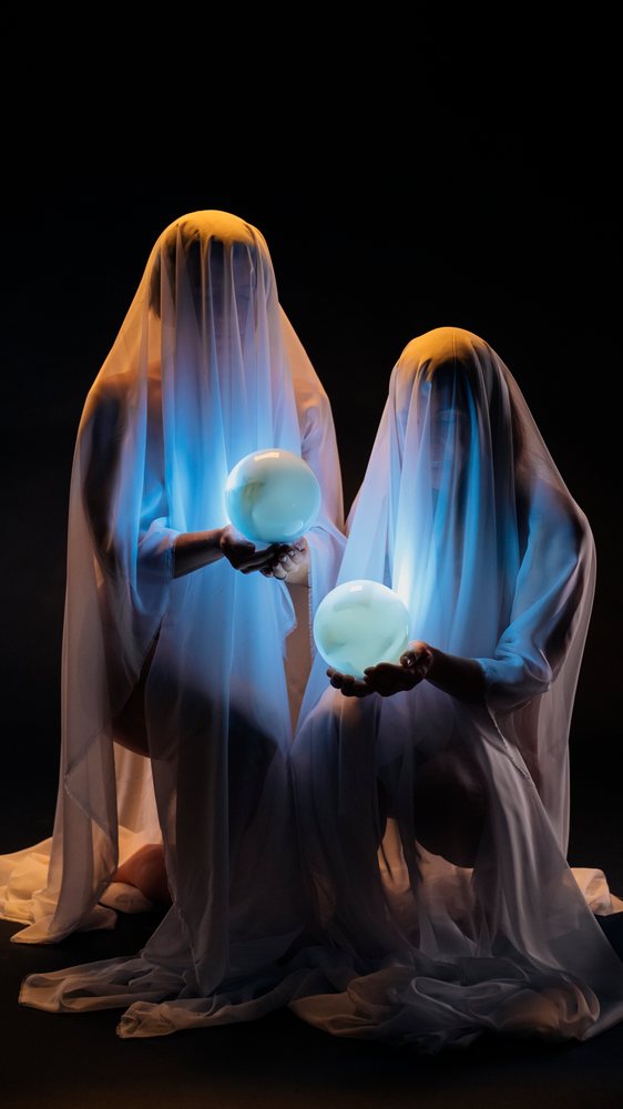Two ghosts holding glowing crystal balls in a dark setting