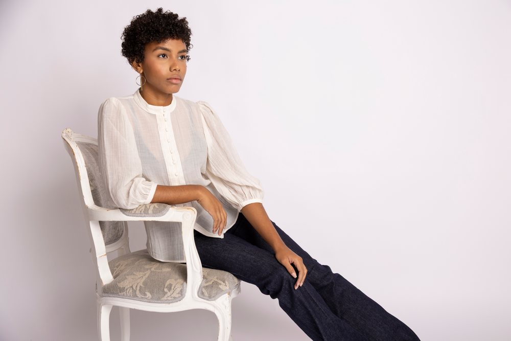 Hispanic woman sitting on vintage chair wearing white blouse