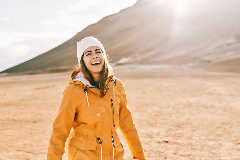 A white woman enjoys the sunny mountain landscape outdoors