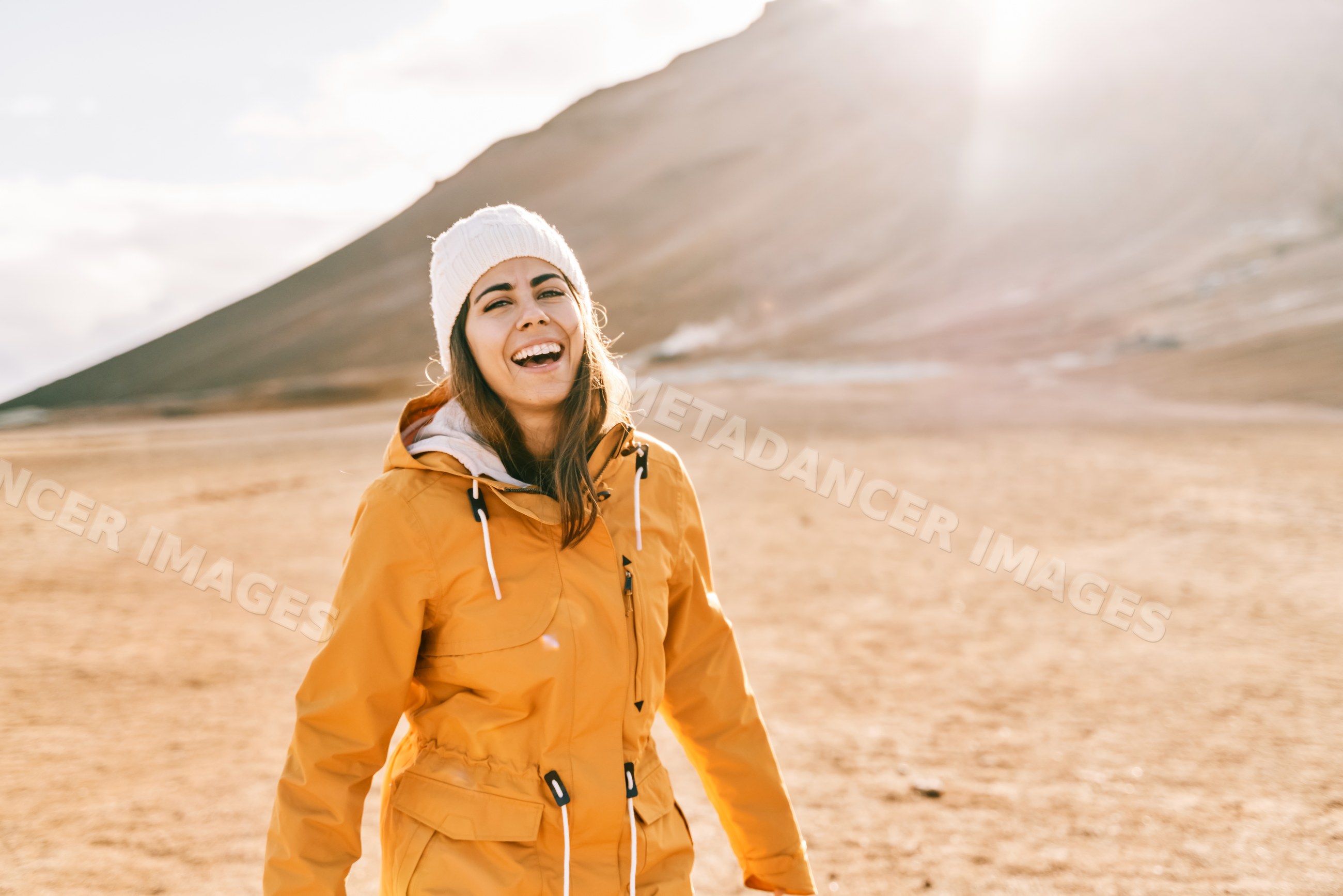A white woman enjoys the sunny mountain landscape outdoors