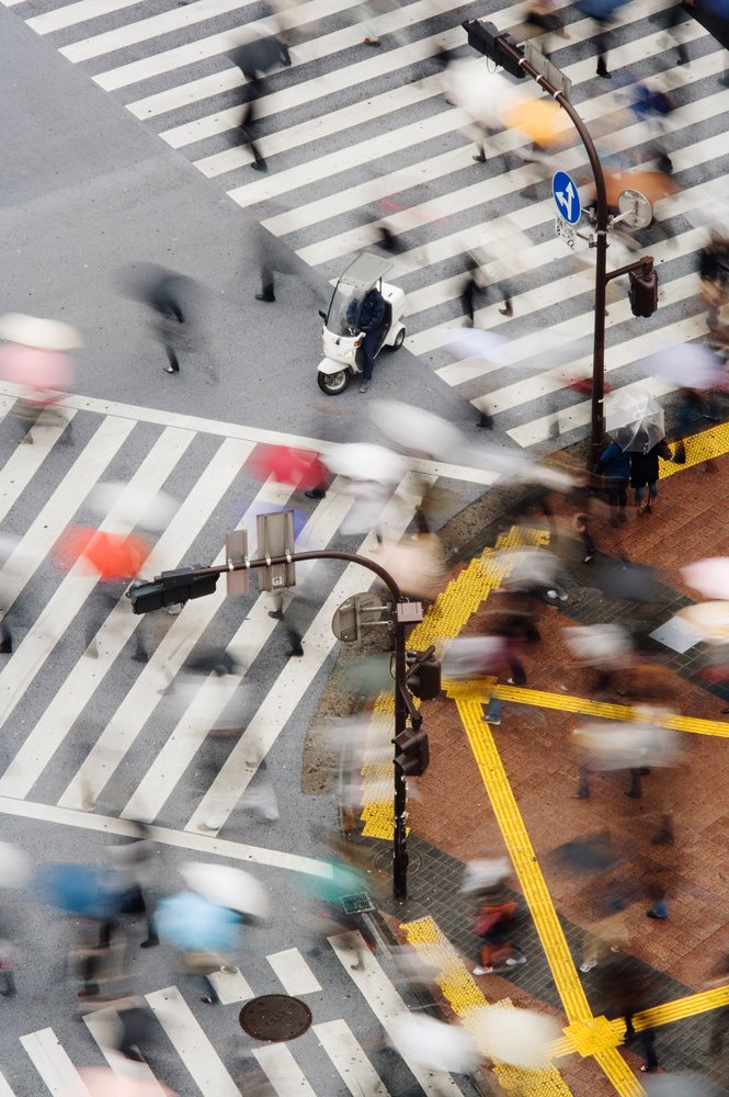 Pedestrians with umbrellas crossing busy shibuya crossing