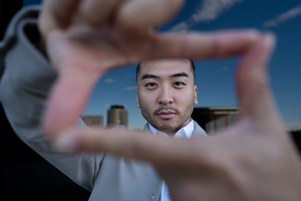 Man framing face with fingers outdoors in urban setting