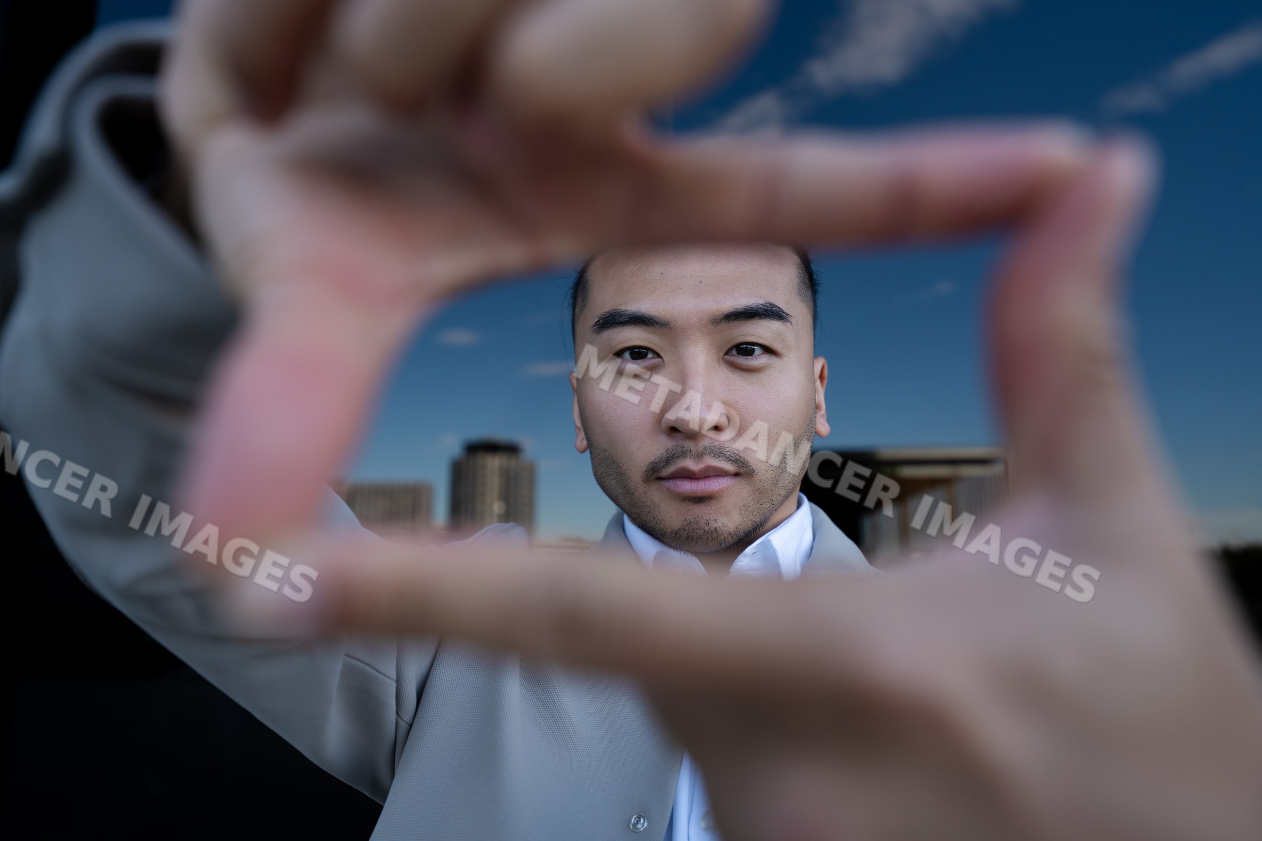 Man framing face with fingers outdoors in urban setting