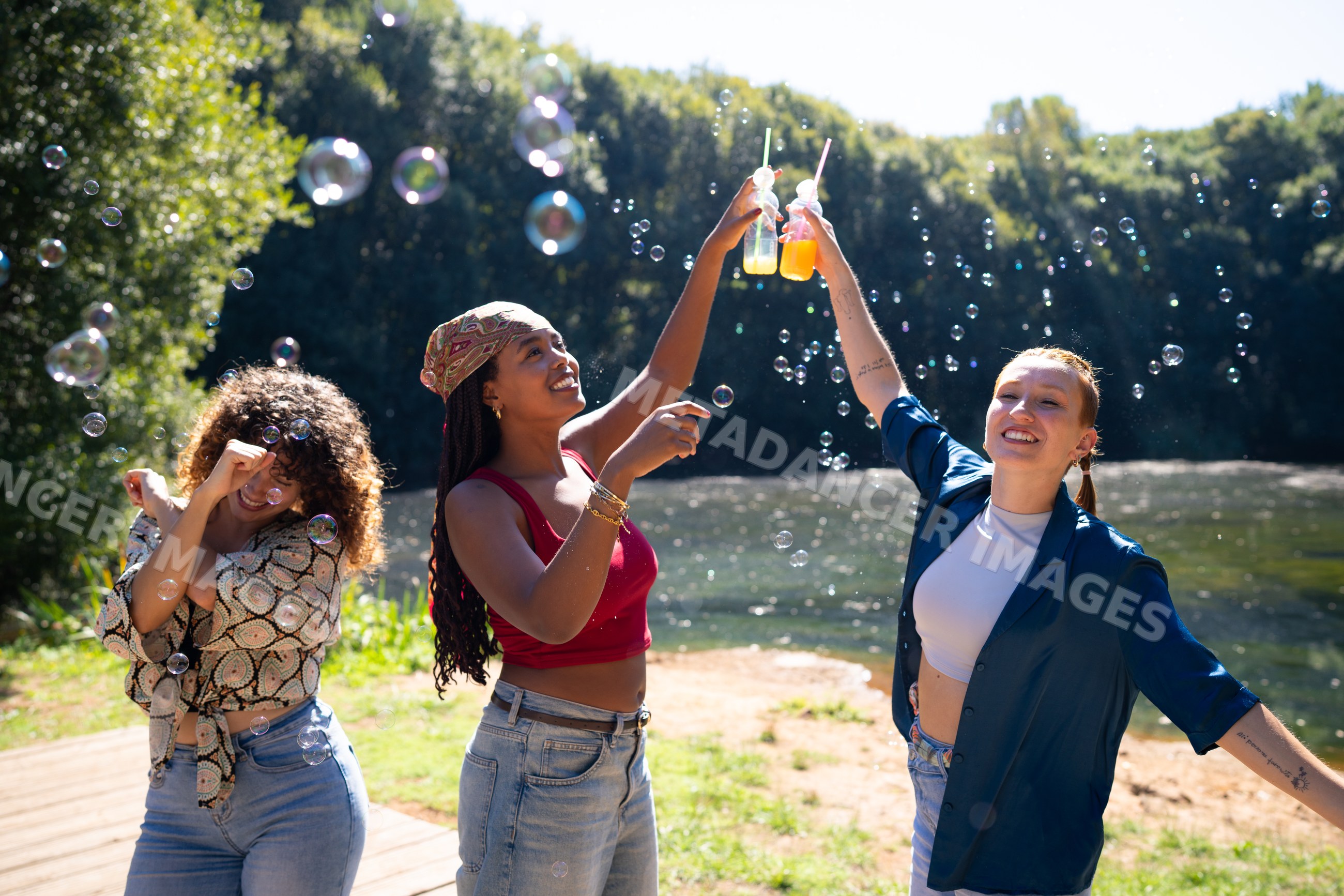 Friends toasting with drinks and bubbles outdoors by a lake