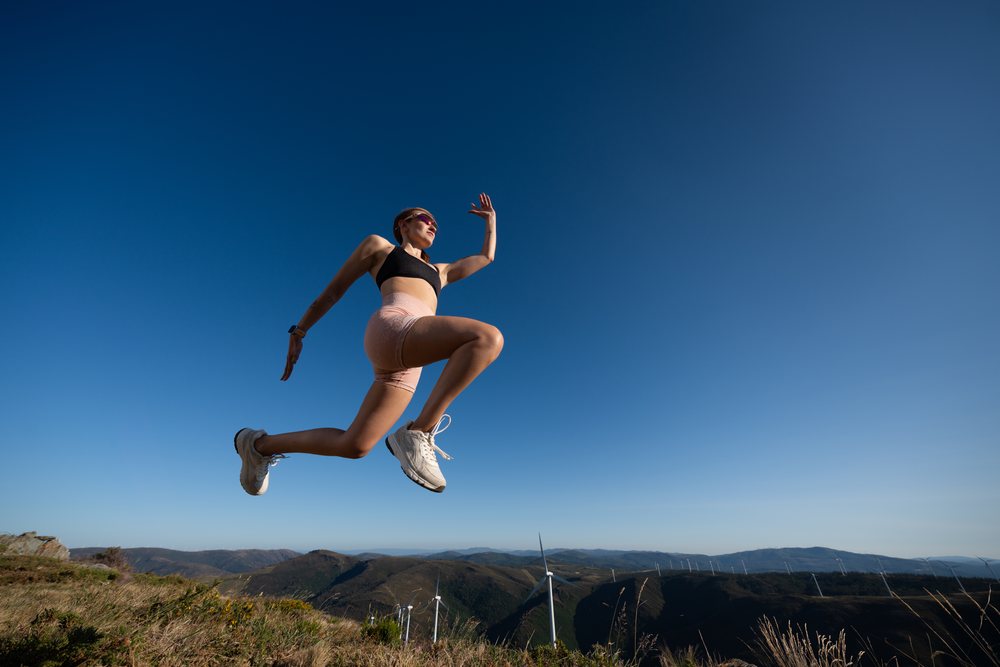 A white woman jumps energetically during an outdoor workout in Galicia