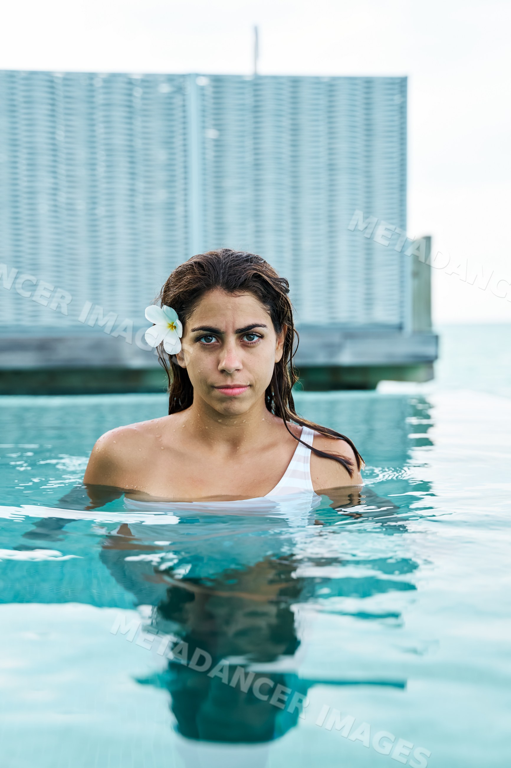 A white woman stands in a swimming pool relaxing during her vacation