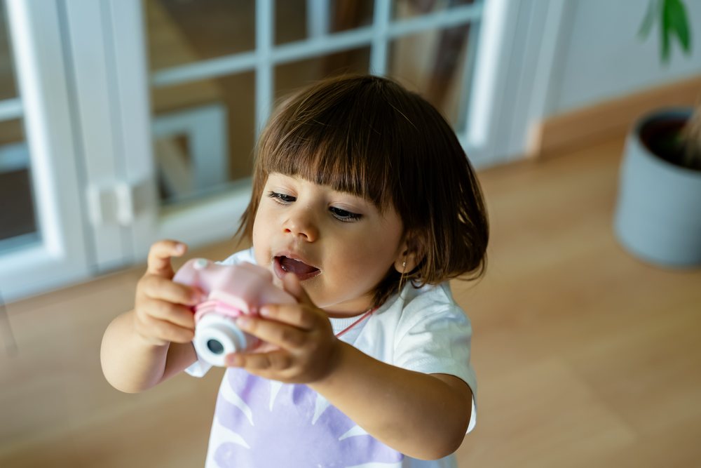 Toddler playing with toy camera indoors at home in Spain