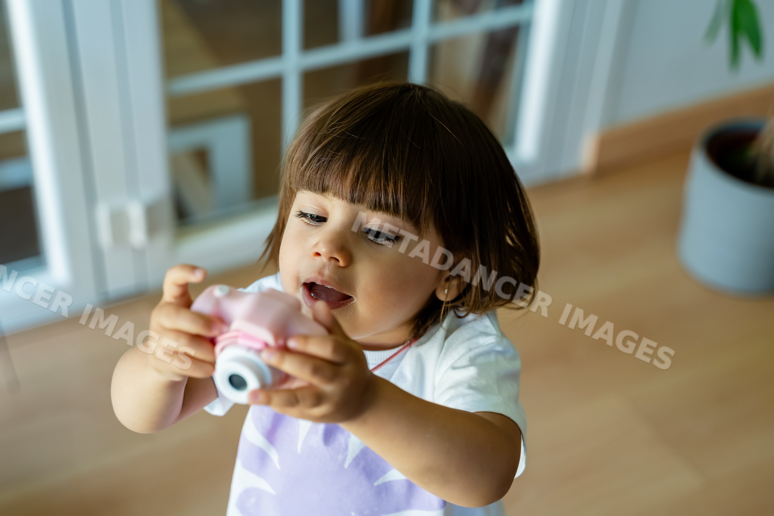 Toddler playing with toy camera indoors at home in Spain