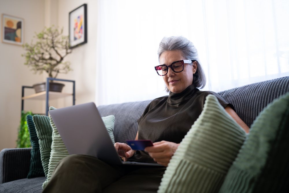 Senior white woman shopping online on laptop in living room