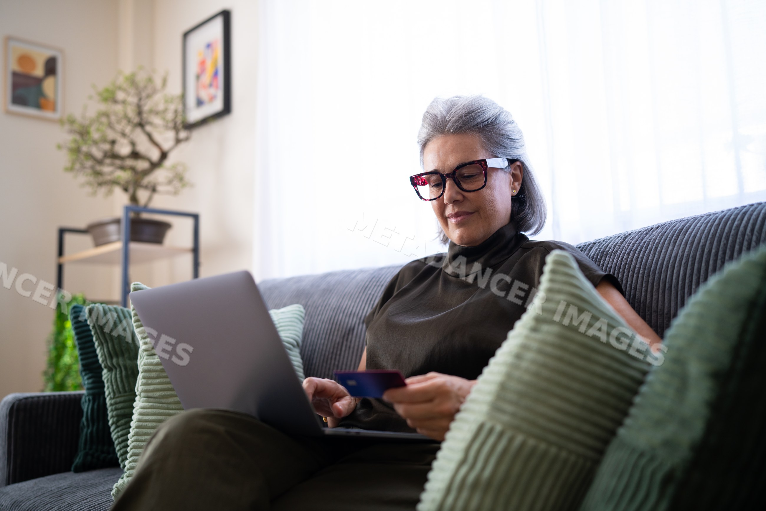 Senior white woman shopping online on laptop in living room