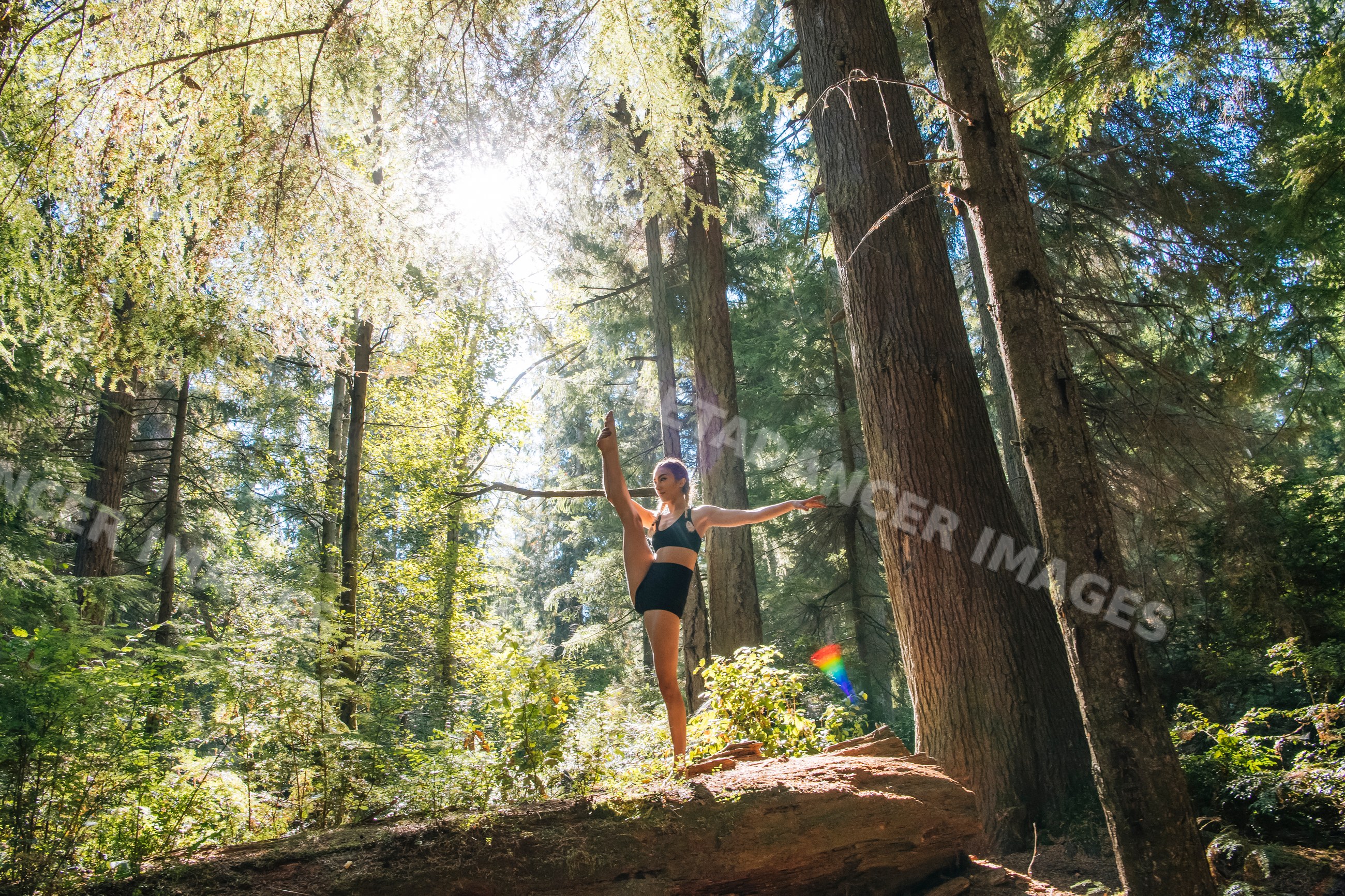 Contortionist stretching and balancing in a sunlit forest