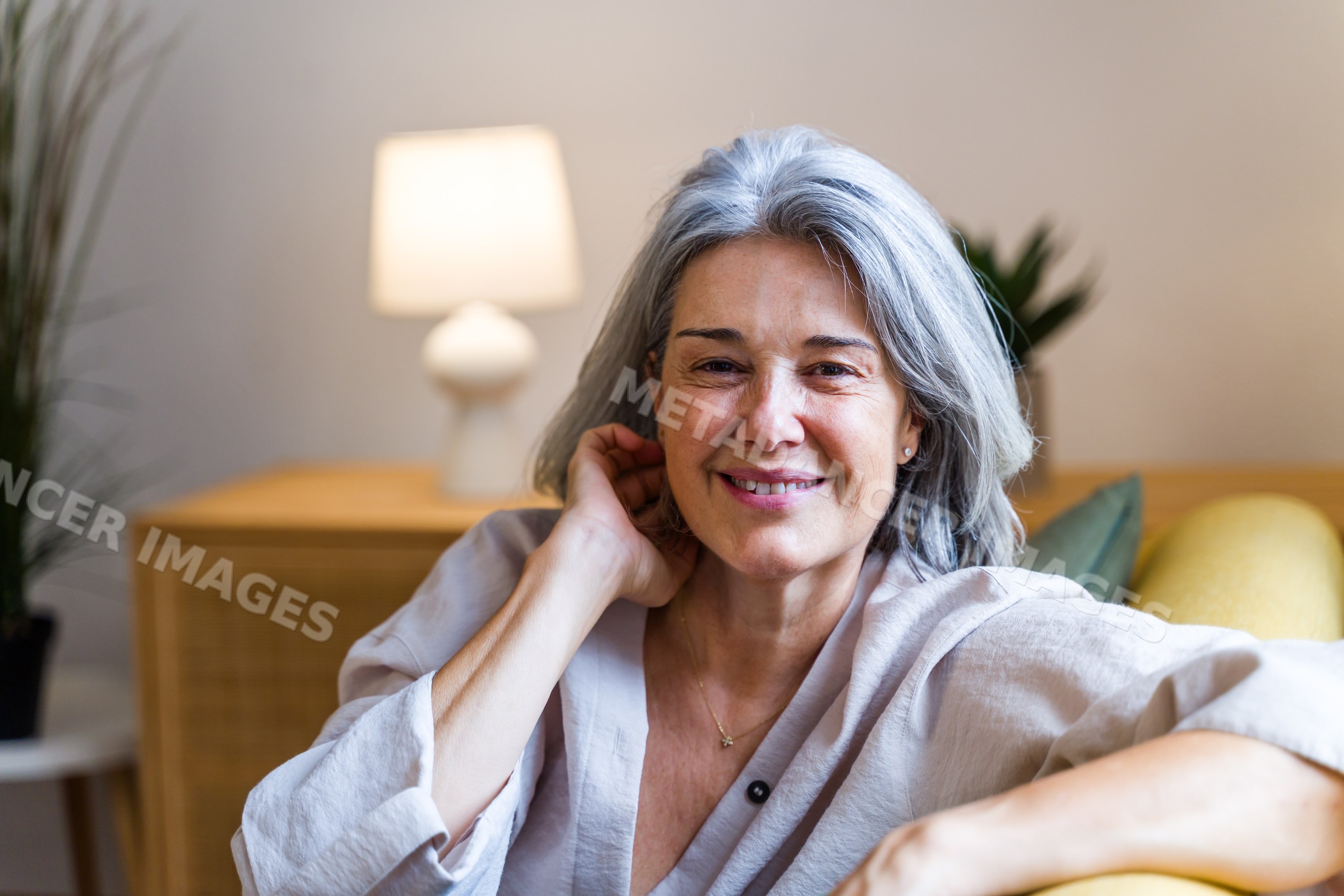 Smiling white woman with gray hair relaxing indoors on a couch