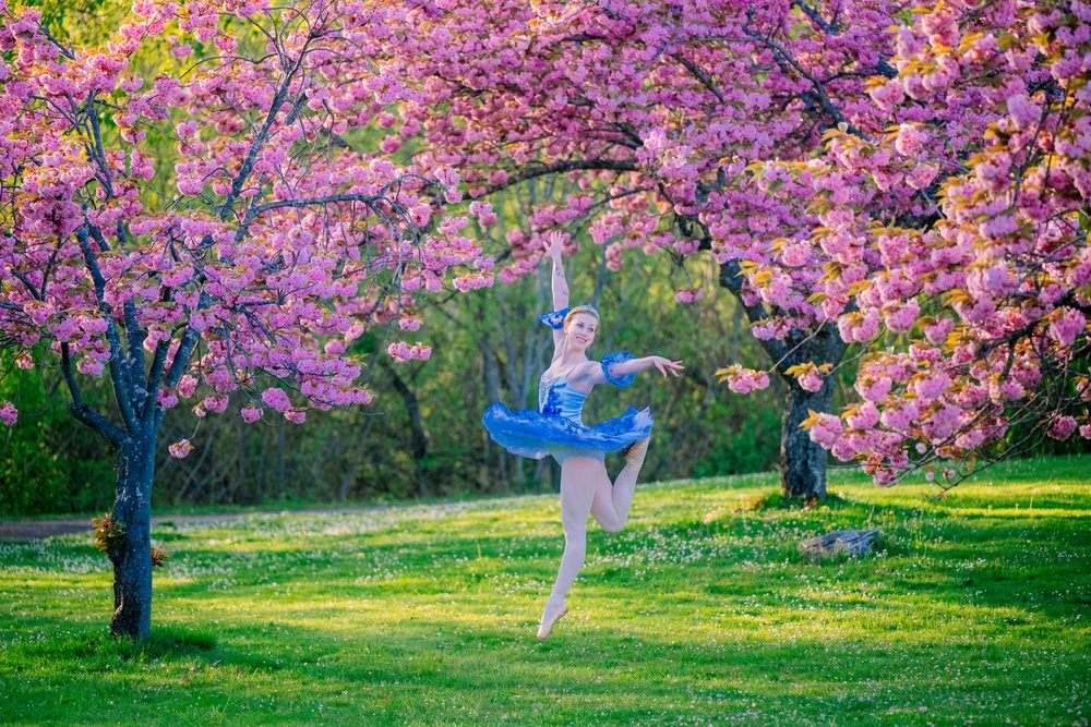 A ballet dancer leaps gracefully outdoors