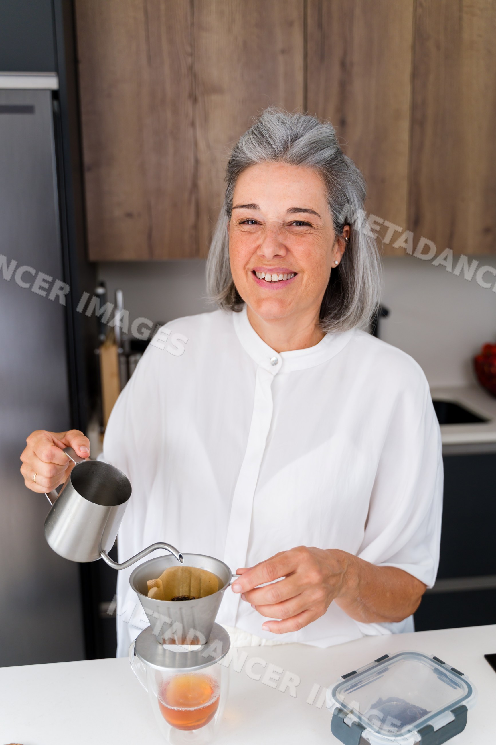 White Woman making coffee with metal dripper in a kitchen in Spain