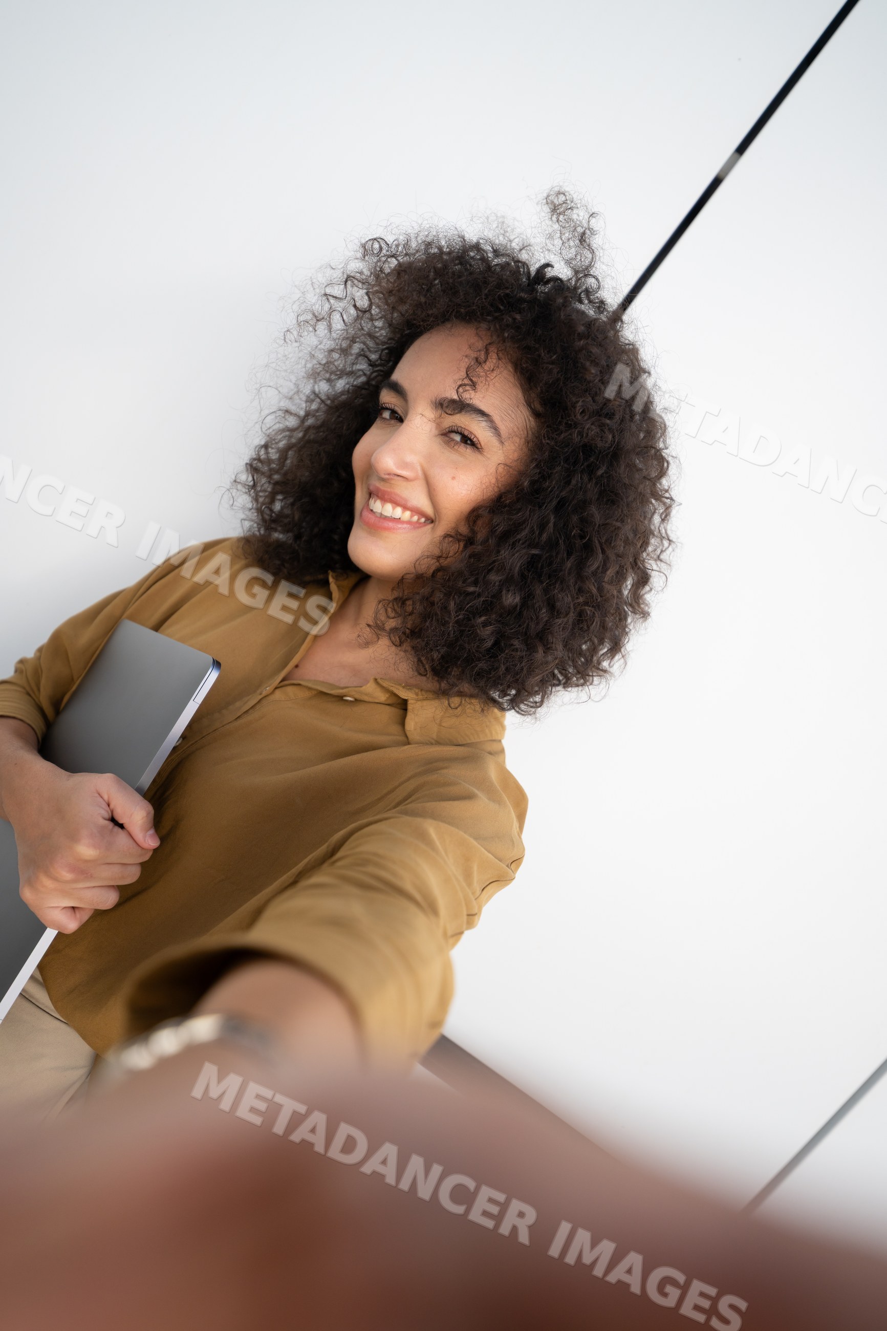 Woman holding laptop smiling taking selfie indoors in office