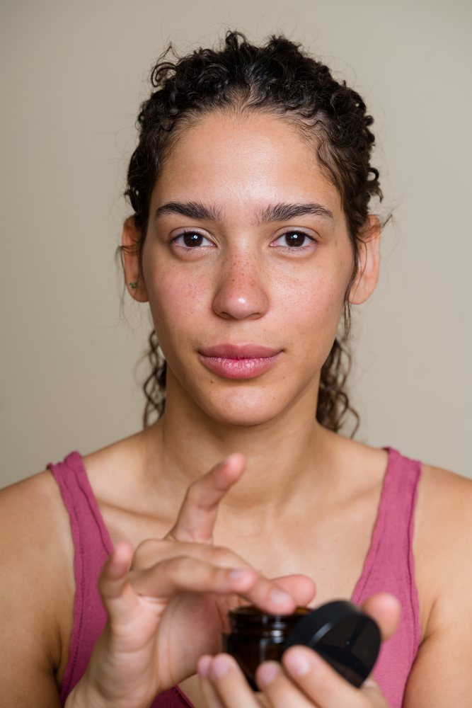 Hispanic woman applying skincare cream in Spain studio beauty shoot