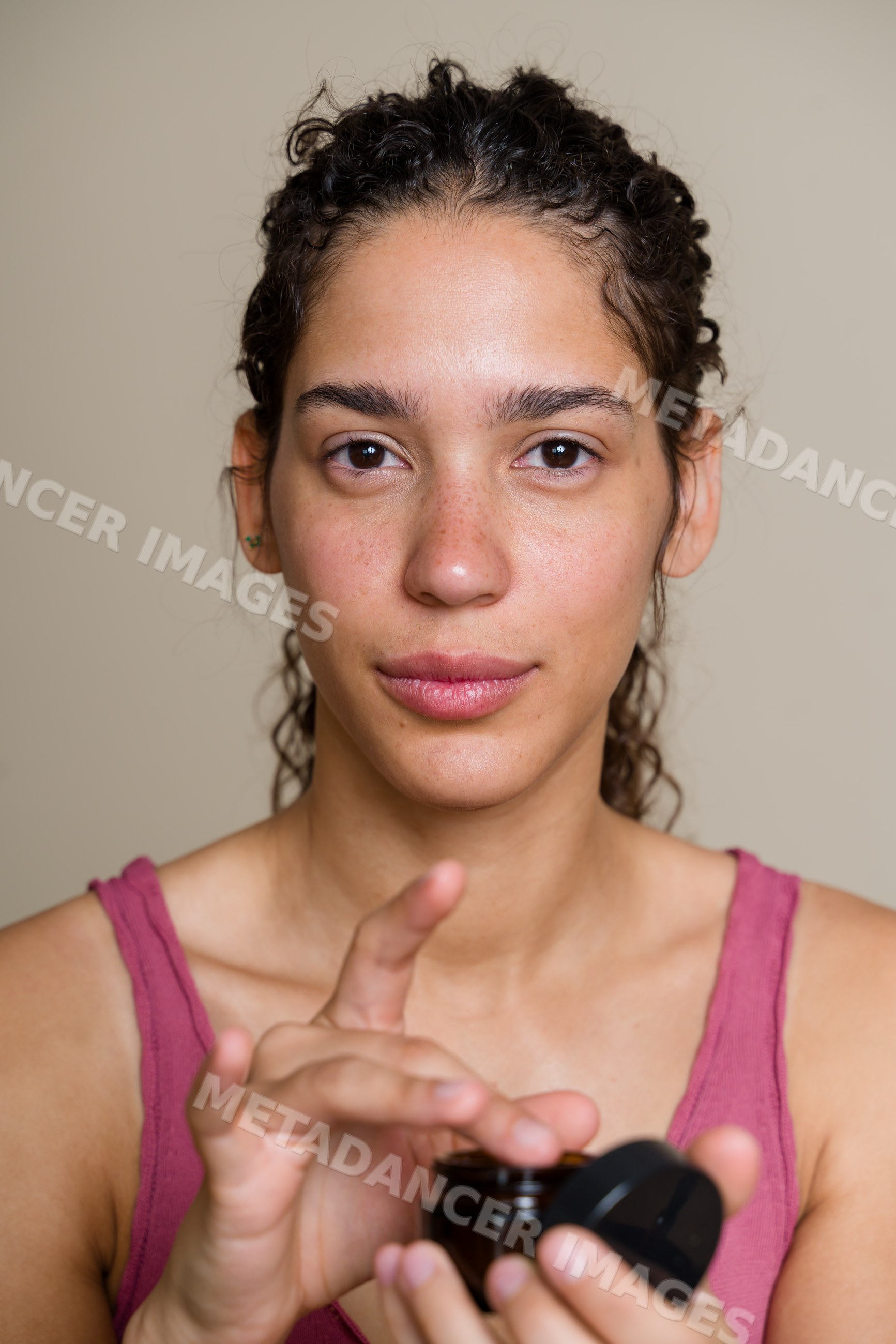 Hispanic woman applying skincare cream in Spain studio beauty shoot