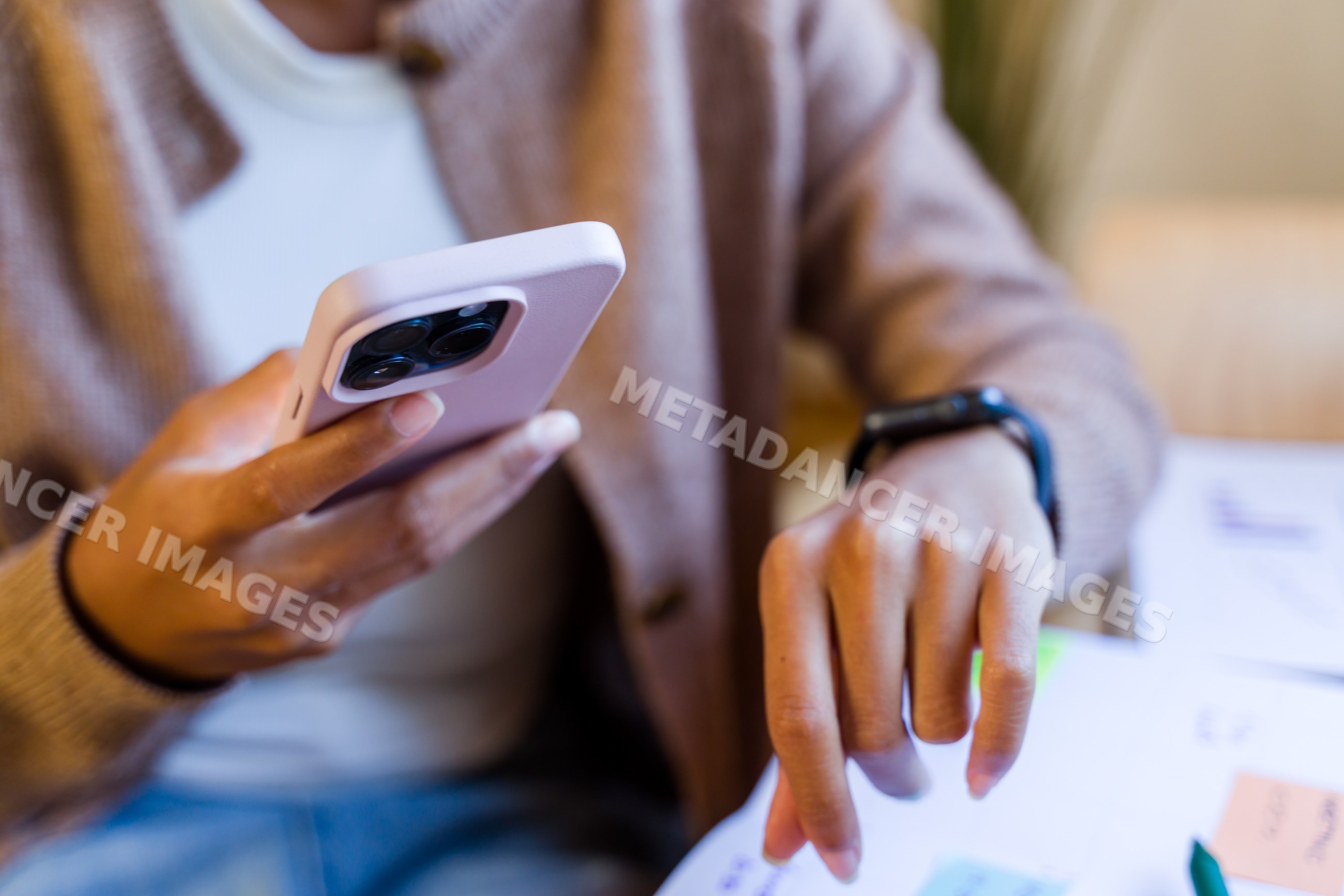 African American person holding phone and interacting with workspace