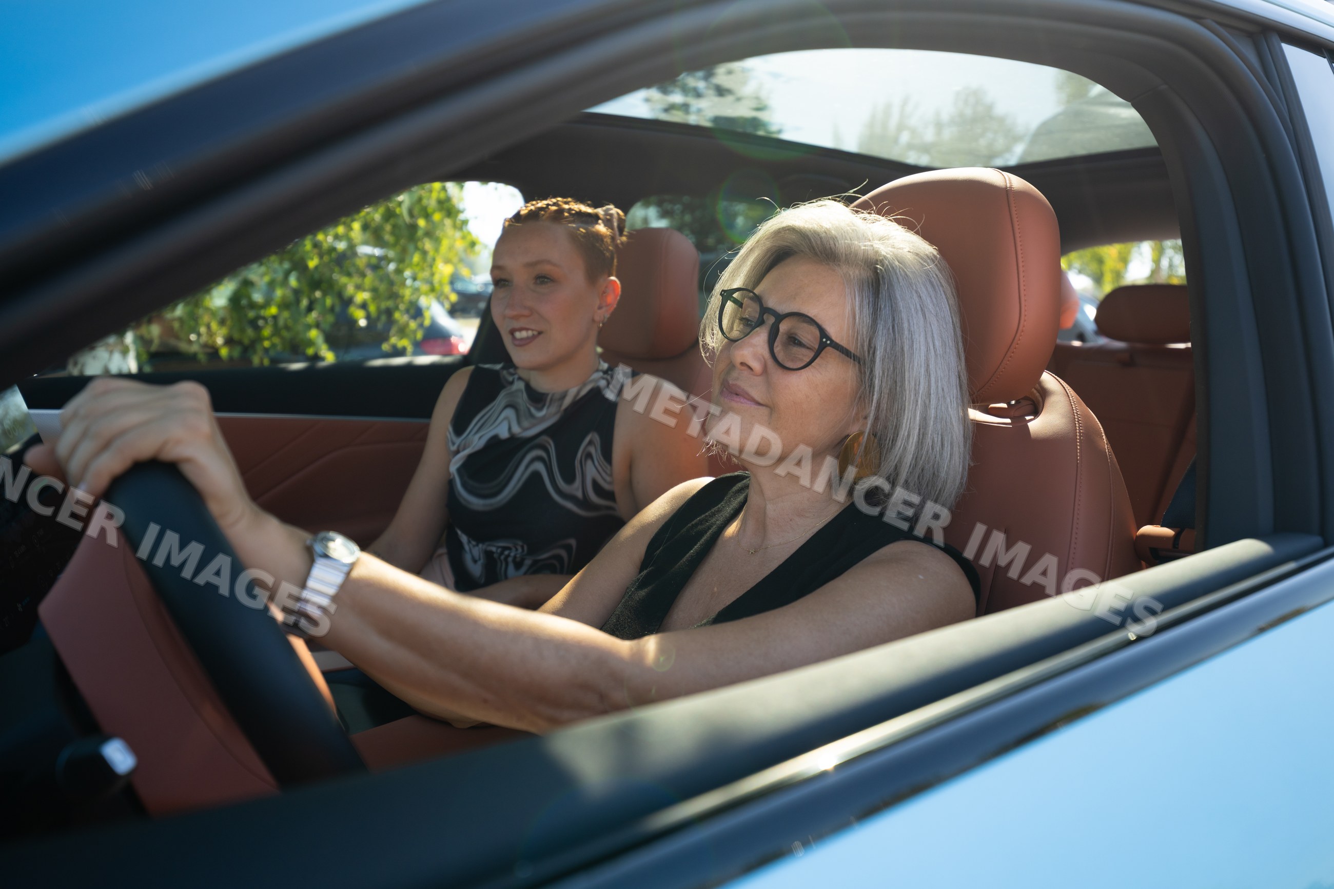 White woman driving car with passenger on sunny day