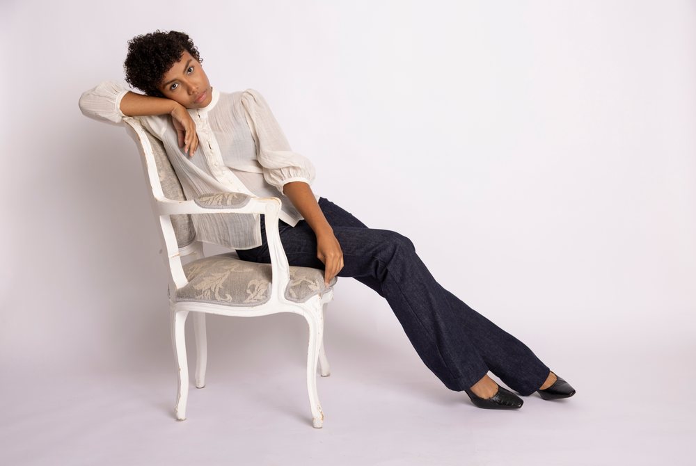 Hispanic woman posing seated on vintage white chair