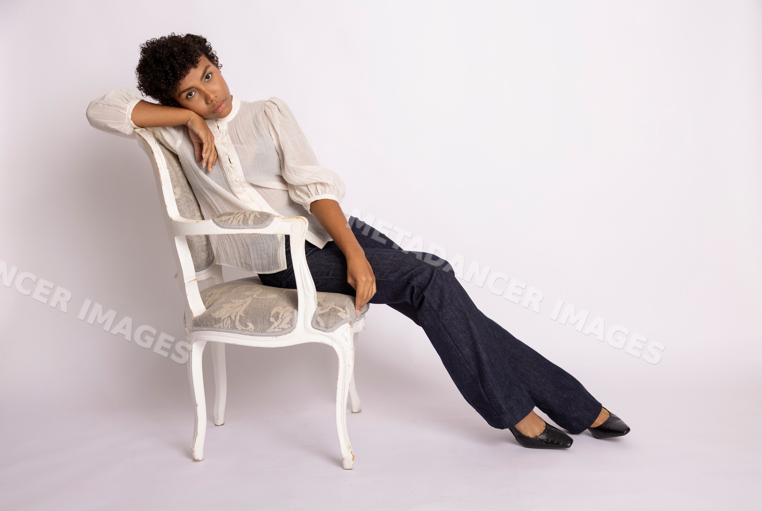 Hispanic woman posing seated on vintage white chair