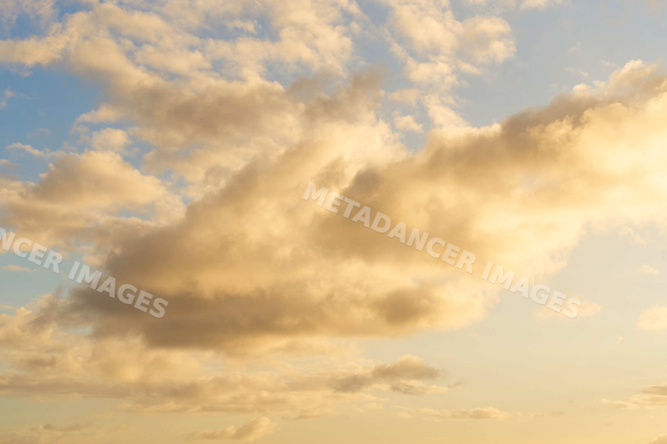 Golden clouds drifting in a clear blue sky at sunset over Oahu, Hawaii